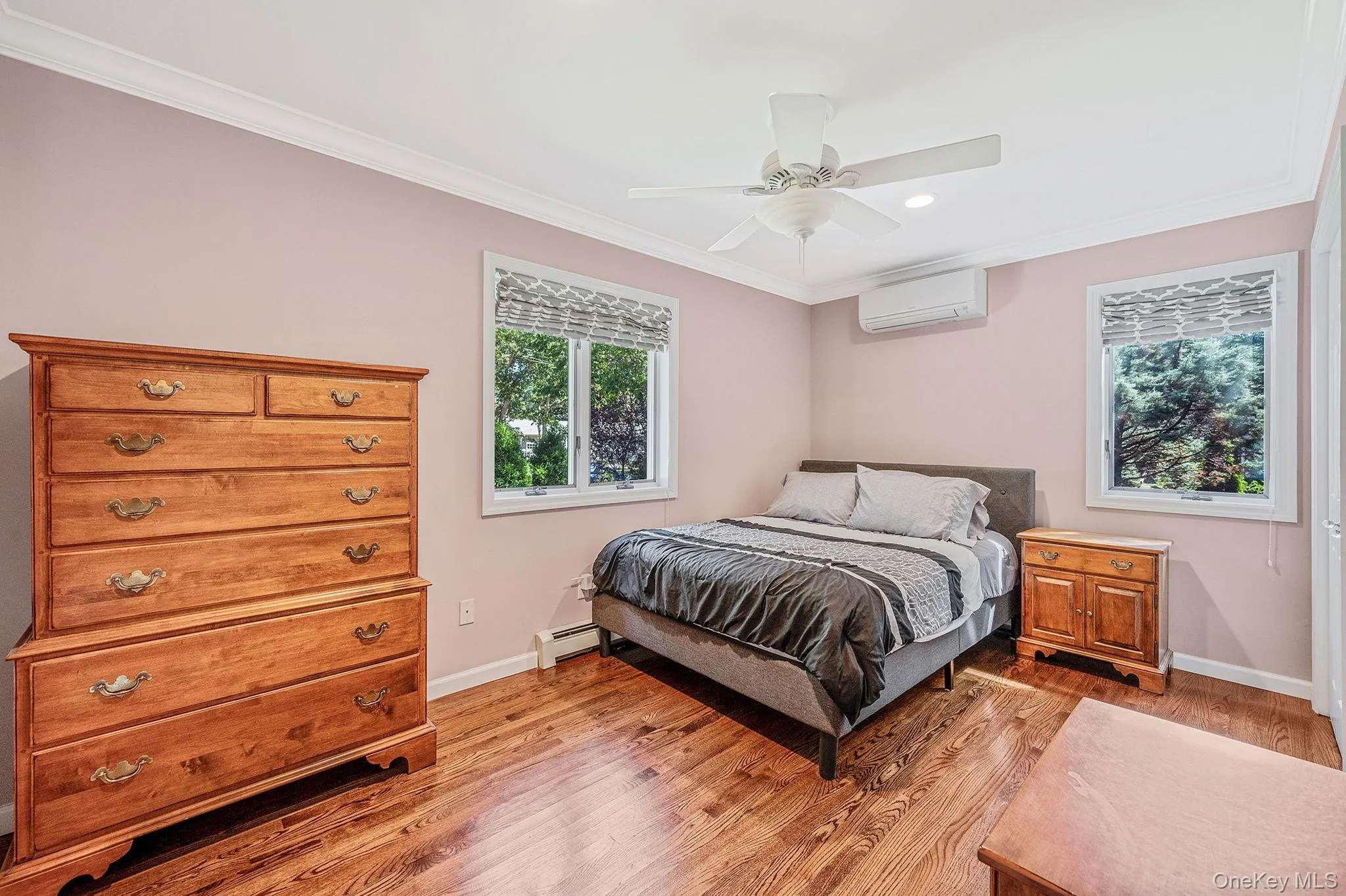Bedroom with ornamental molding, light wood-style floors, a ceiling fan, a wall mounted AC, and a baseboard radiator Bedroom with ornamental molding, light wood-style floors, a ceiling fan, a wall mounted AC, and a baseboard radiator