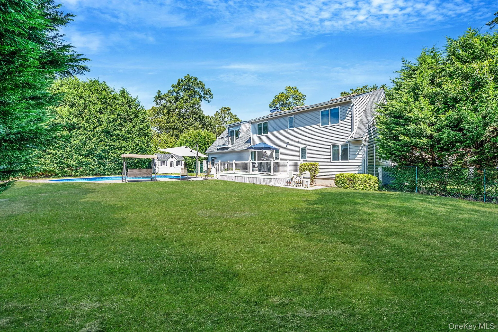 Rear view of property with a wooden deck, an outdoor pool, and an outbuilding Rear view of property with a wooden deck, an outdoor pool, and an outbuilding