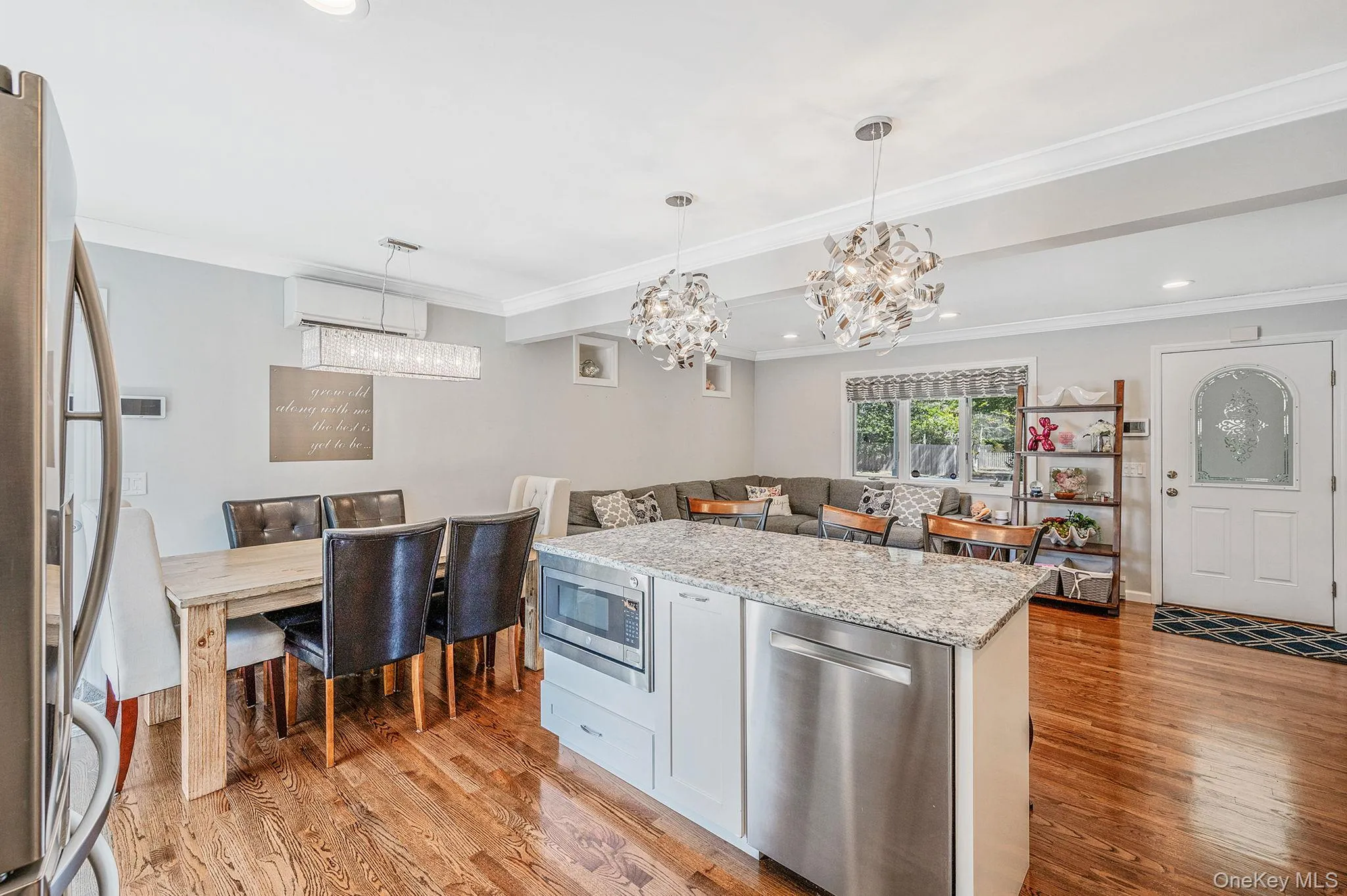 Kitchen featuring appliances with stainless steel finishes, light stone counters, light wood-type flooring, decorative light fixtures, and a center island Kitchen featuring appliances with stainless steel finishes, light stone counters, light wood-type flooring, decorative light fixtures, and a center island