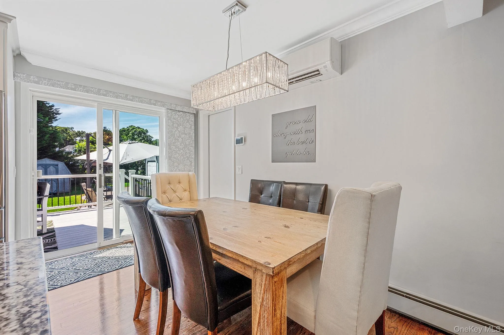 Dining room featuring a baseboard radiator, ornamental molding, wood finished floors, a wall unit AC, and a chandelier Dining room featuring a baseboard radiator, ornamental molding, wood finished floors, a wall unit AC, and a chandelier