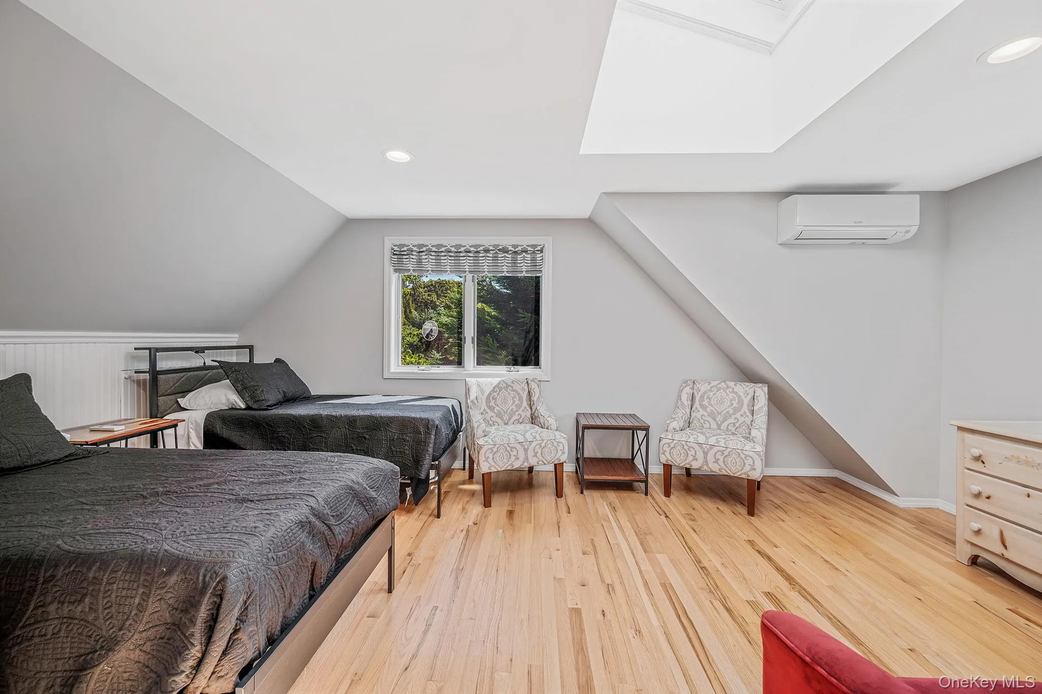 Bedroom with light wood finished floors, vaulted ceiling, recessed lighting, a skylight, and a wall unit AC Bedroom with light wood finished floors, vaulted ceiling, recessed lighting, a skylight, and a wall unit AC