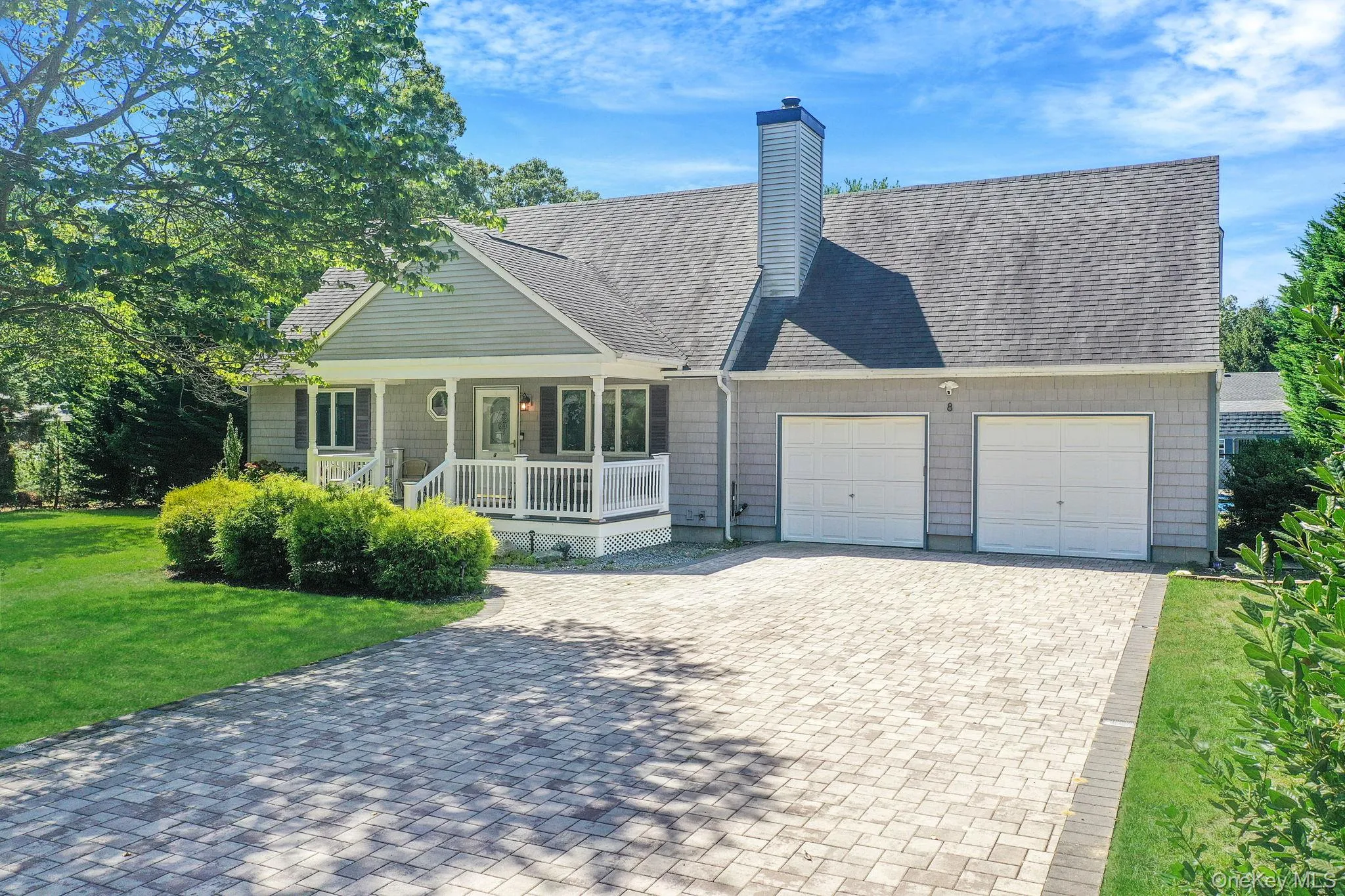 View of front of property featuring a porch, a shingled roof, decorative driveway, and a front lawn View of front of property featuring a porch, a shingled roof, decorative driveway, and a front lawn