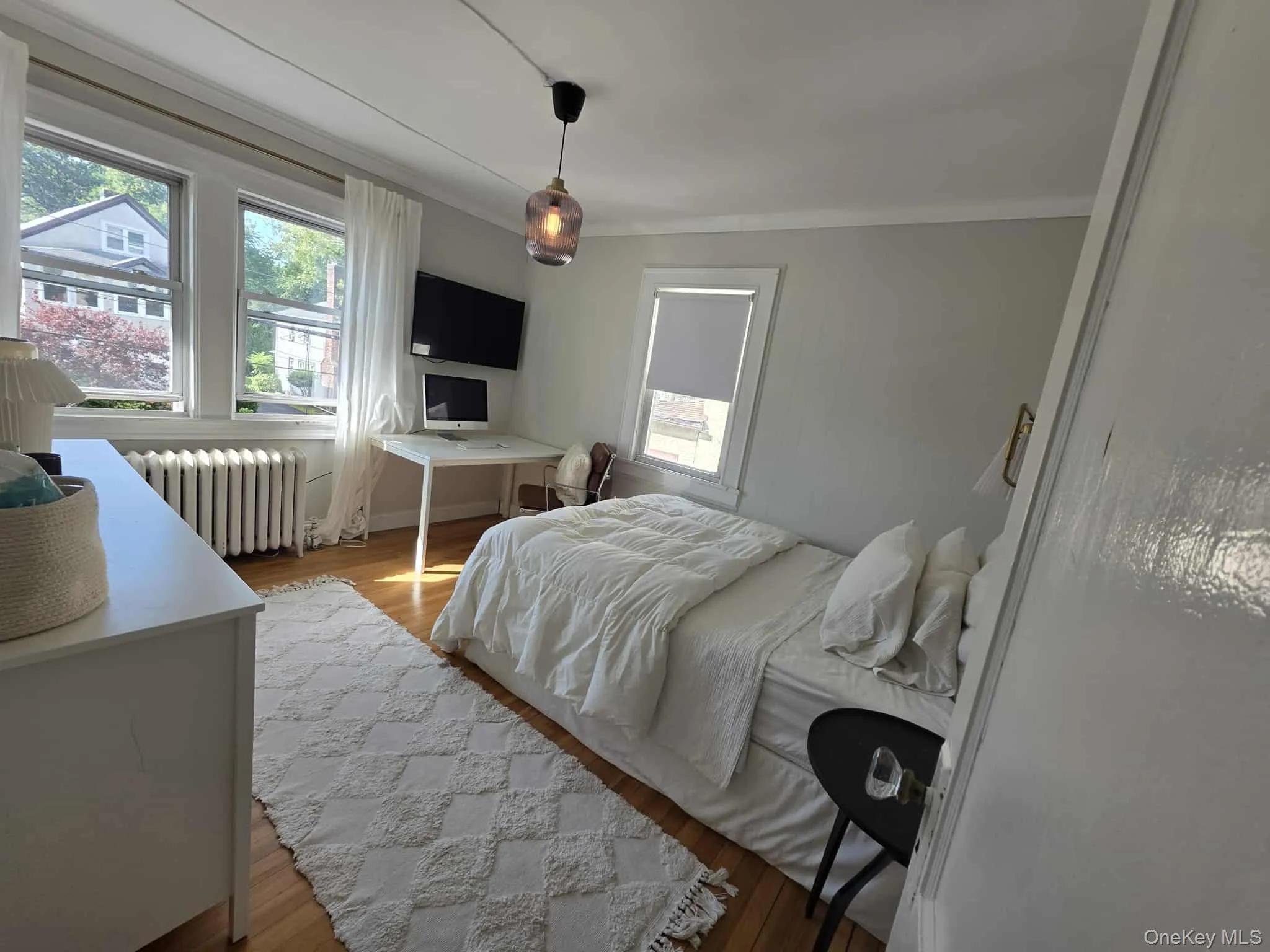 Bedroom featuring wood finished floors, radiator, multiple windows, and ornamental molding Bedroom featuring wood finished floors, radiator, multiple windows, and ornamental molding