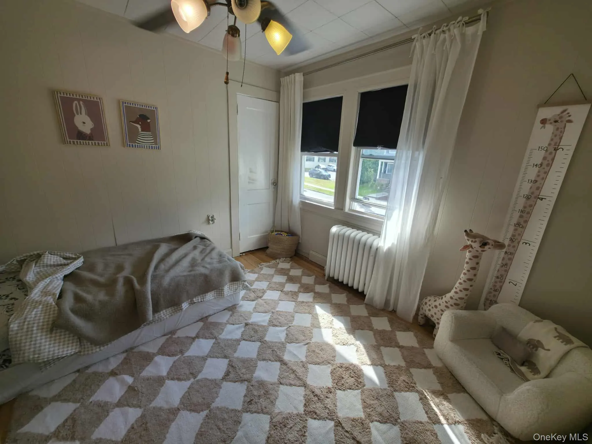 Bedroom with radiator, wood finished floors, and a ceiling fan Bedroom with radiator, wood finished floors, and a ceiling fan
