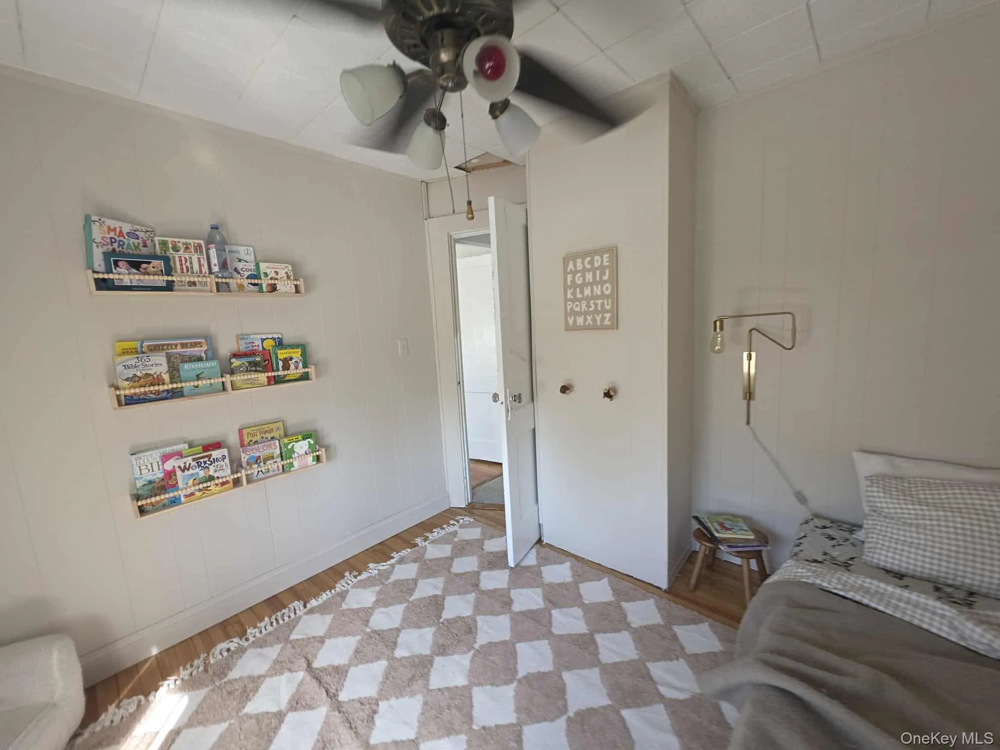 Bedroom featuring light wood-style floors, a ceiling fan, and wooden walls Bedroom featuring light wood-style floors, a ceiling fan, and wooden walls