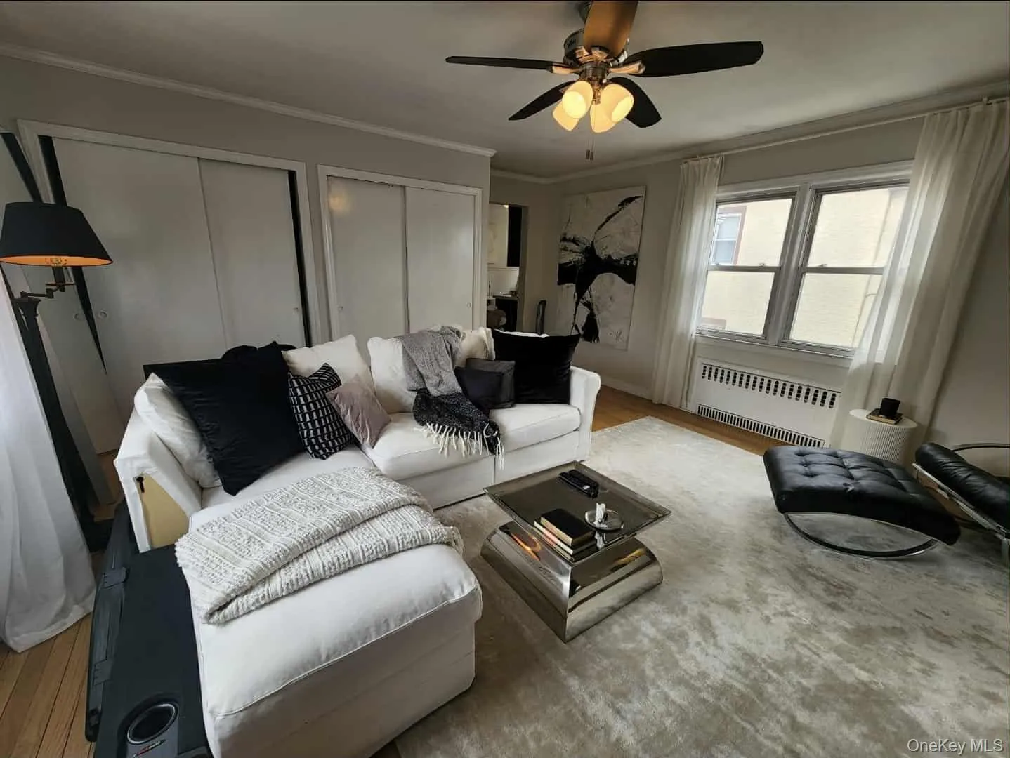 Living room with radiator heating unit, crown molding, wood finished floors, and a ceiling fan Living room with radiator heating unit, crown molding, wood finished floors, and a ceiling fan