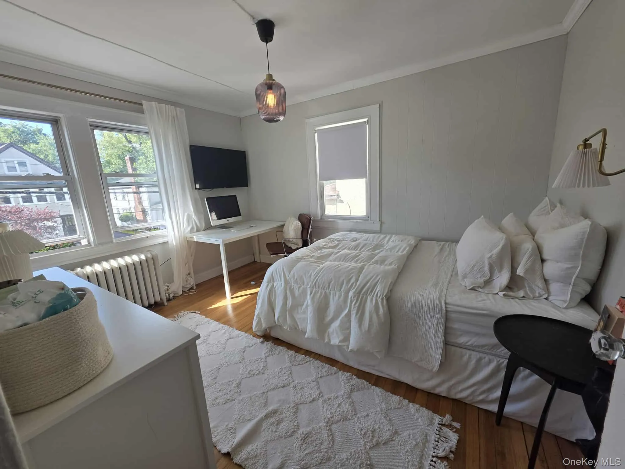 Bedroom with wood finished floors, radiator, and crown molding Bedroom with wood finished floors, radiator, and crown molding