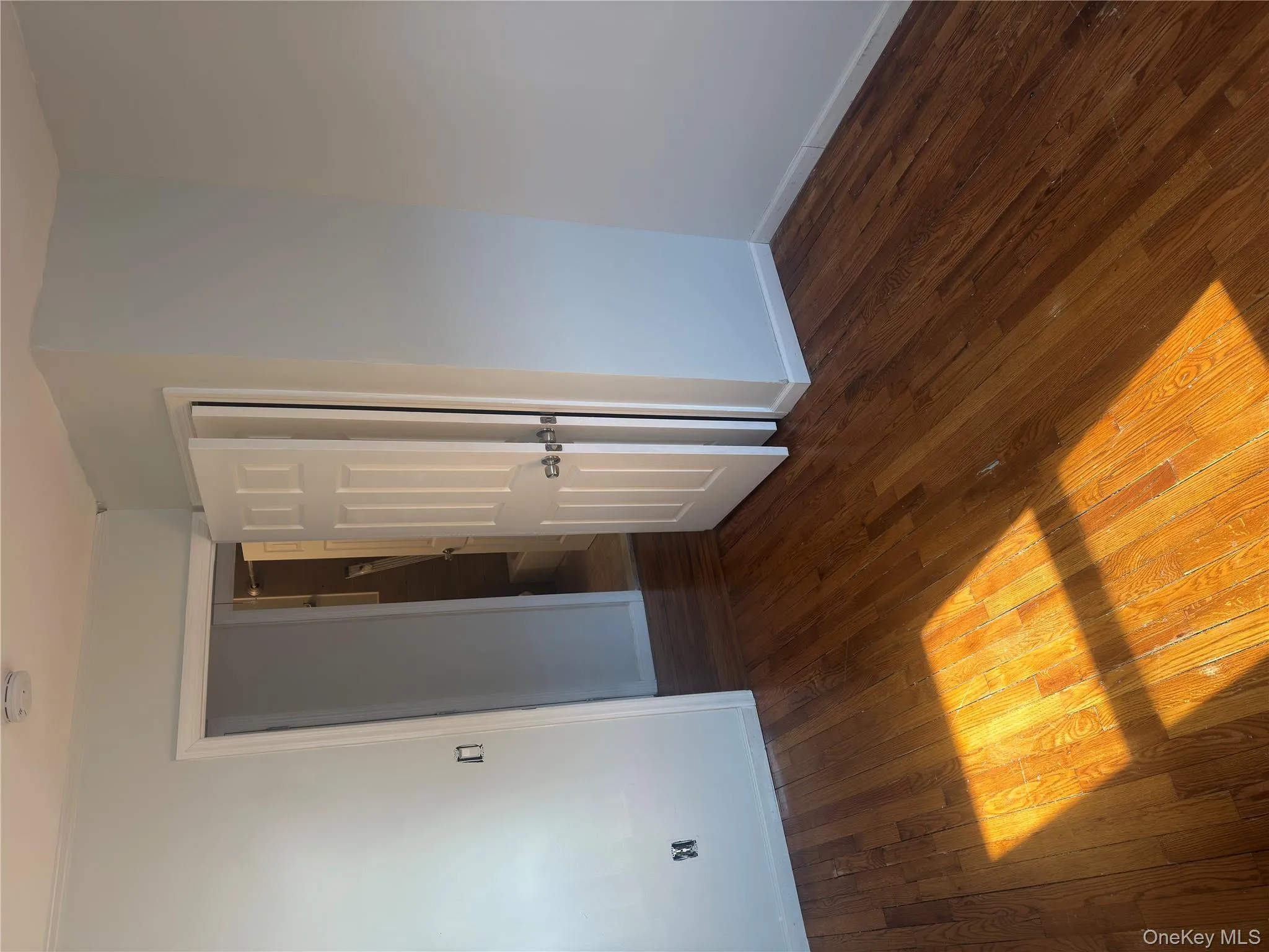 Empty room featuring dark wood-style floors and a smoke detector Empty room featuring dark wood-style floors and a smoke detector