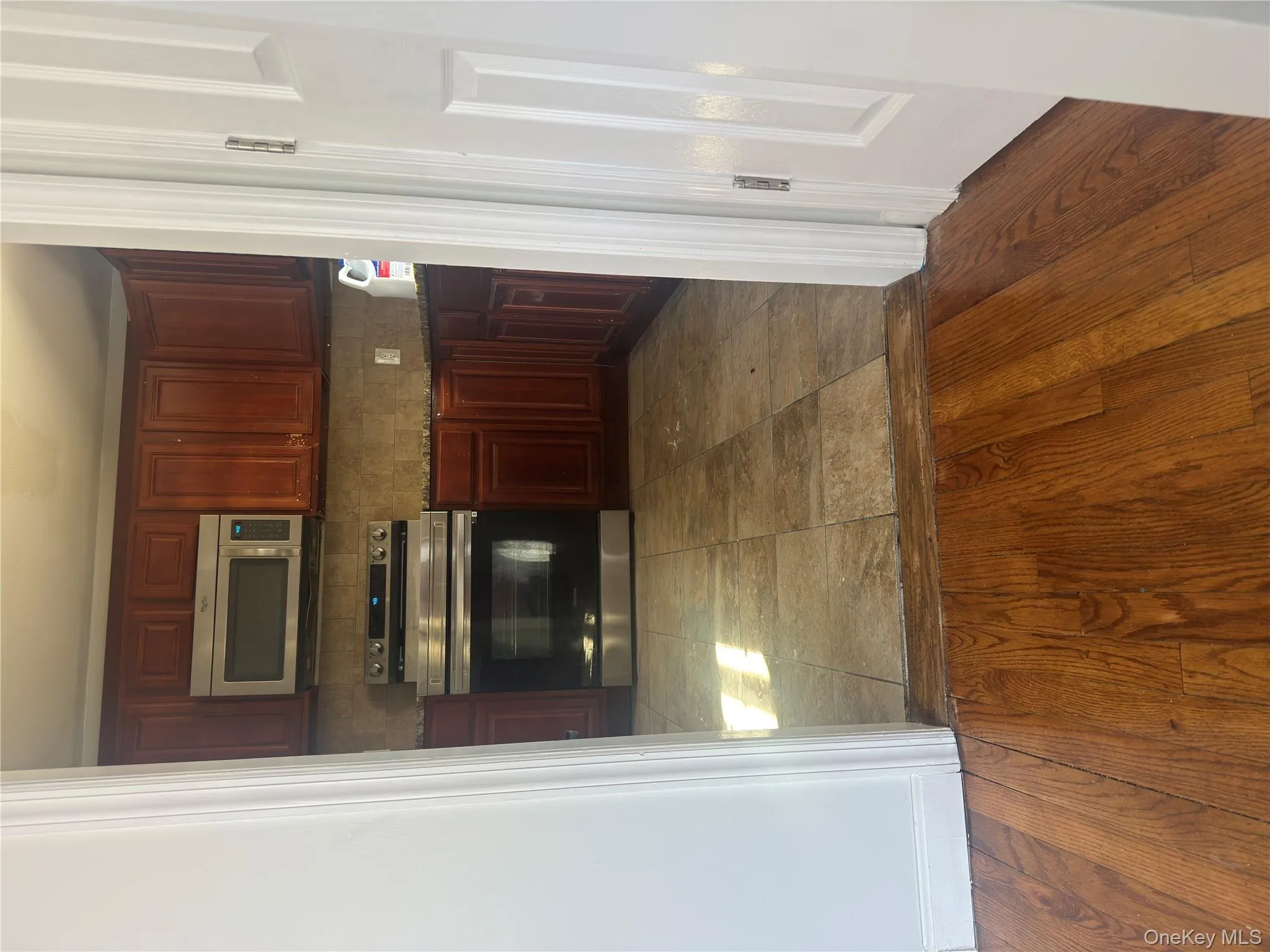 Kitchen featuring range, dark stone countertops, backsplash, and reddish brown cabinets Kitchen featuring range, dark stone countertops, backsplash, and reddish brown cabinets