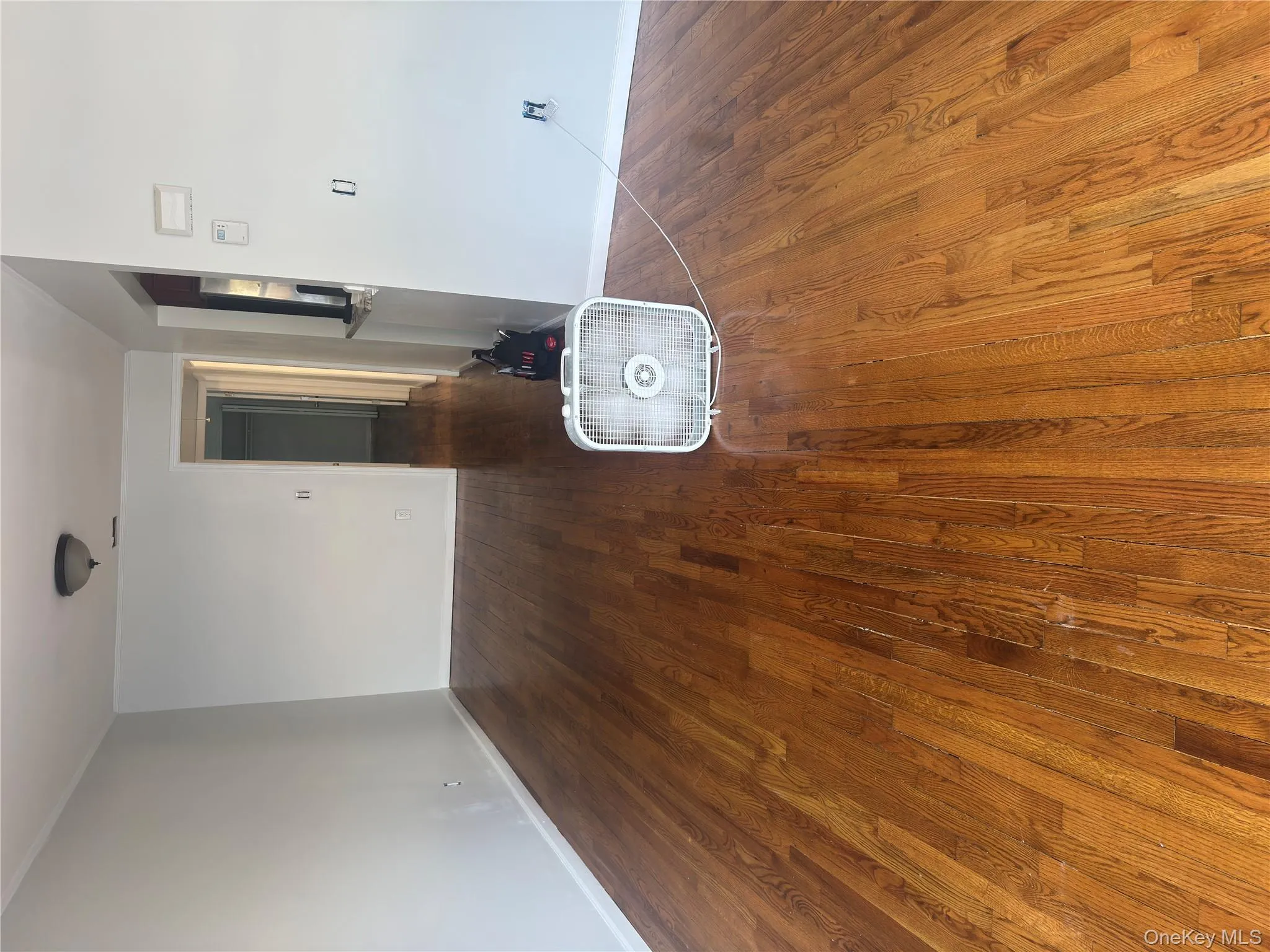 Empty room with dark wood-style flooring and baseboards Empty room with dark wood-style flooring and baseboards
