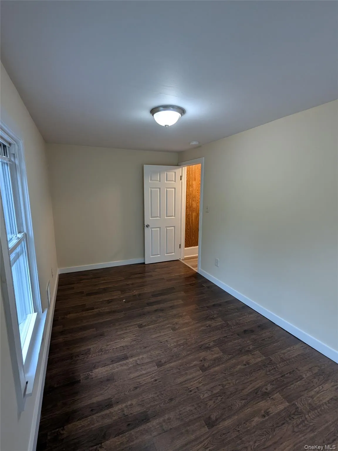 Spare room featuring dark wood-style flooring and baseboards Spare room featuring dark wood-style flooring and baseboards