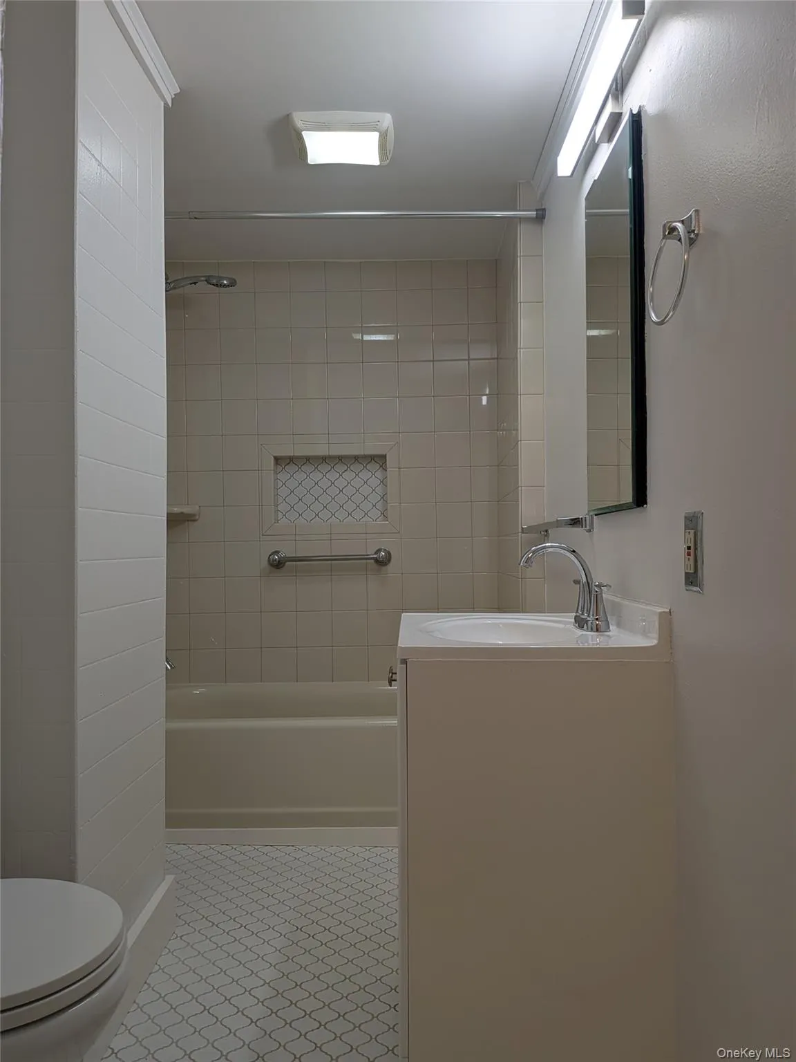 Full bath featuring vanity, washtub / shower combination, and light tile patterned floors Full bath featuring vanity, washtub / shower combination, and light tile patterned floors