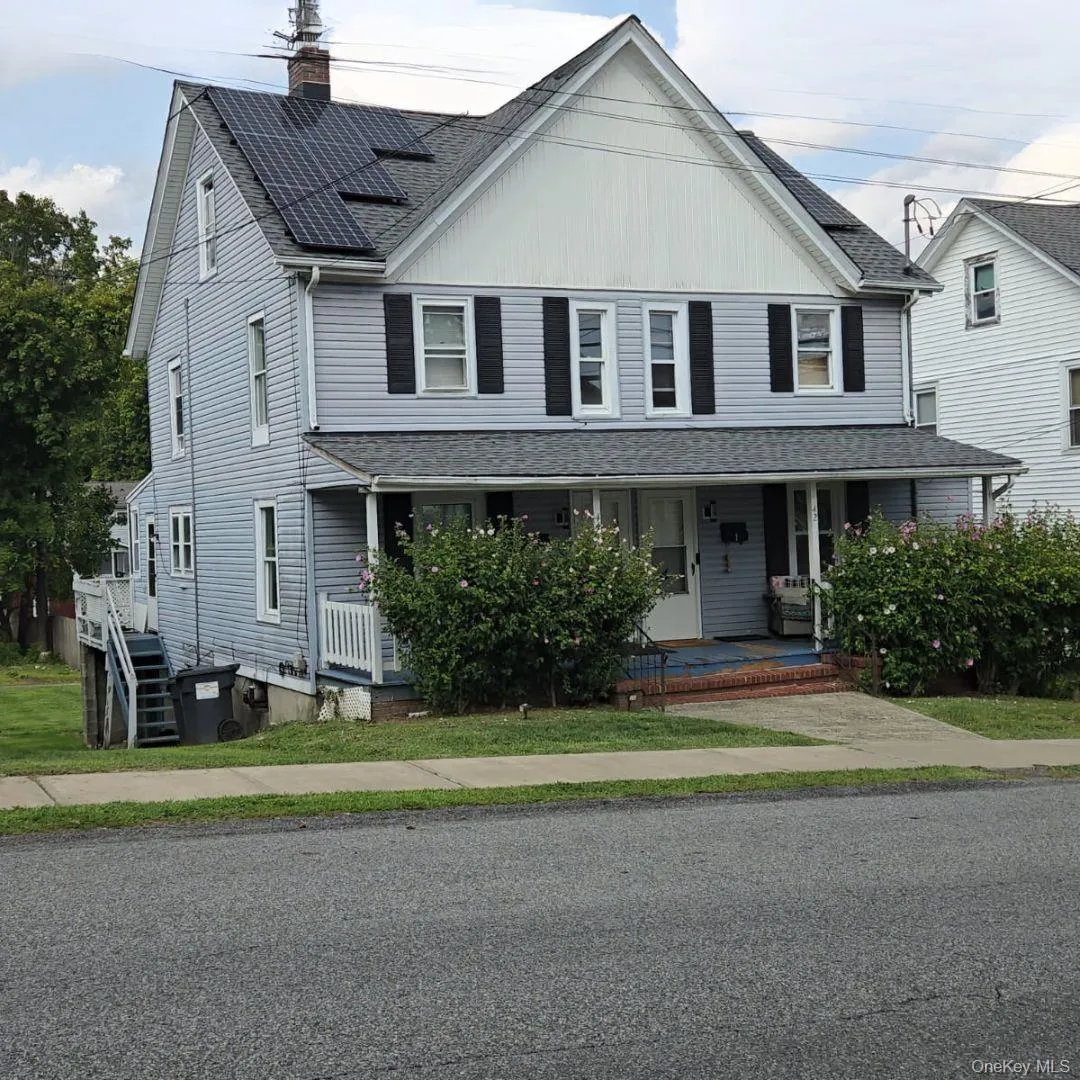 View of front of property featuring covered porch, roof with shingles, a chimney, and solar panels View of front of property featuring covered porch, roof with shingles, a chimney, and solar panels