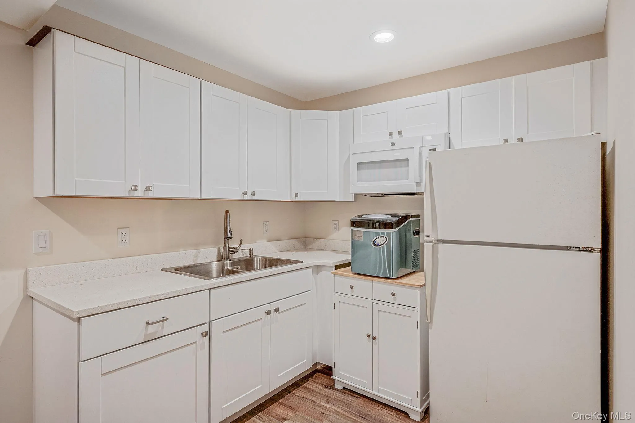 Kitchen featuring white appliances, light countertops, white cabinetry, light wood finished floors, and recessed lighting Kitchen featuring white appliances, light countertops, white cabinetry, light wood finished floors, and recessed lighting