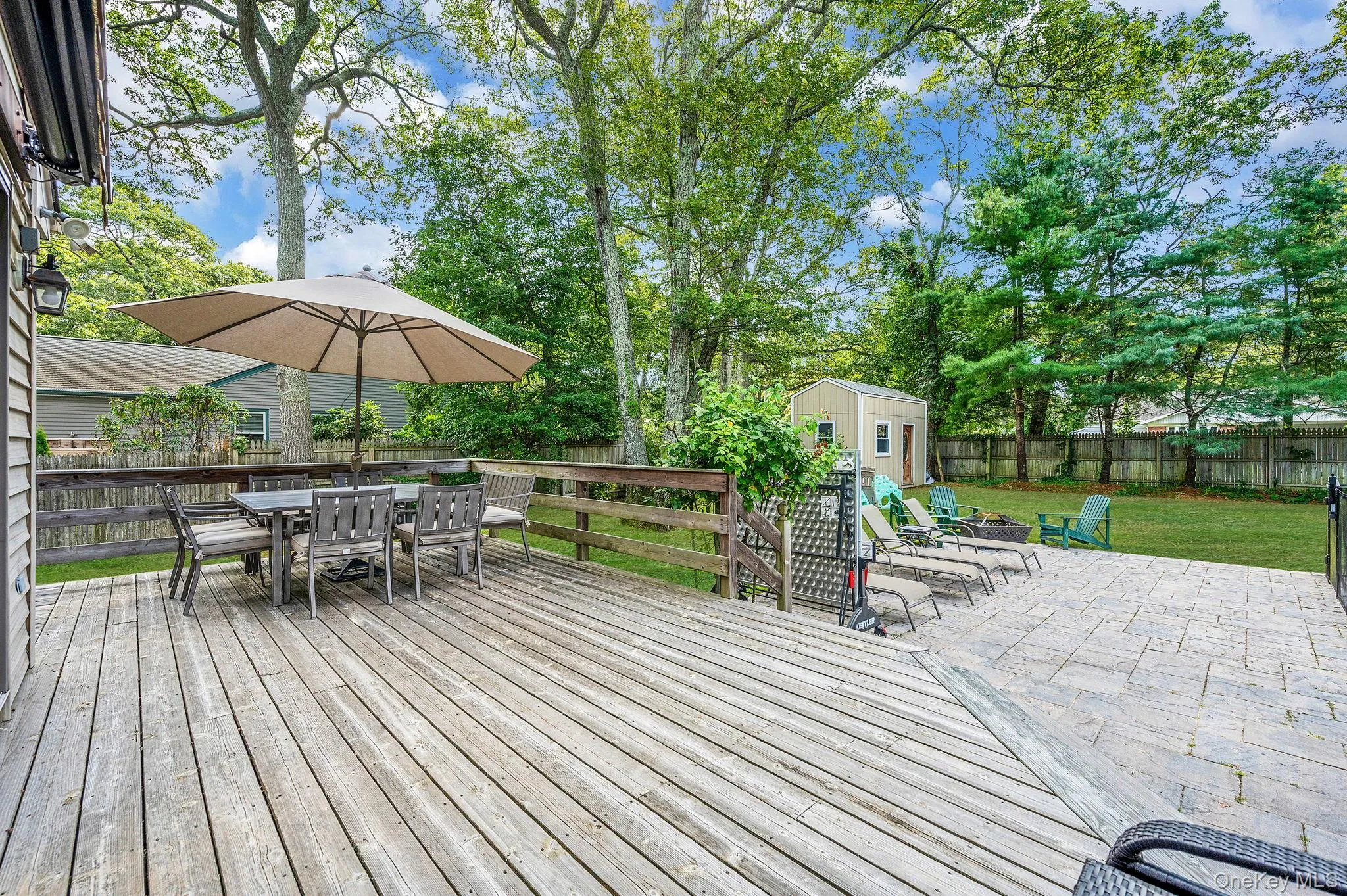 Wooden deck featuring outdoor dining area, a fenced backyard, a shed, and a patio Wooden deck featuring outdoor dining area, a fenced backyard, a shed, and a patio