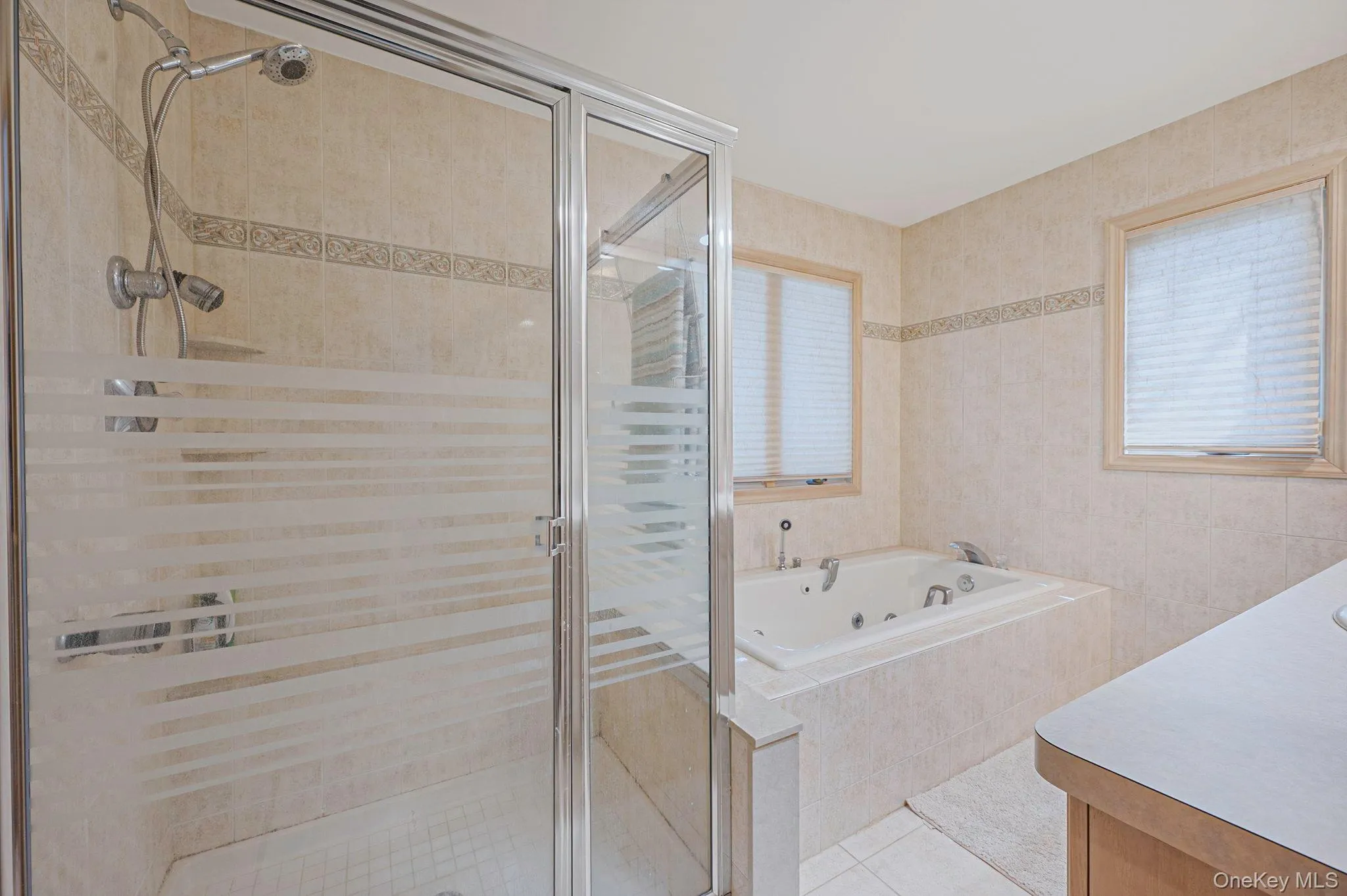 Bathroom with a stall shower, a whirlpool tub, light tile patterned floors, vanity, and tile walls Bathroom with a stall shower, a whirlpool tub, light tile patterned floors, vanity, and tile walls