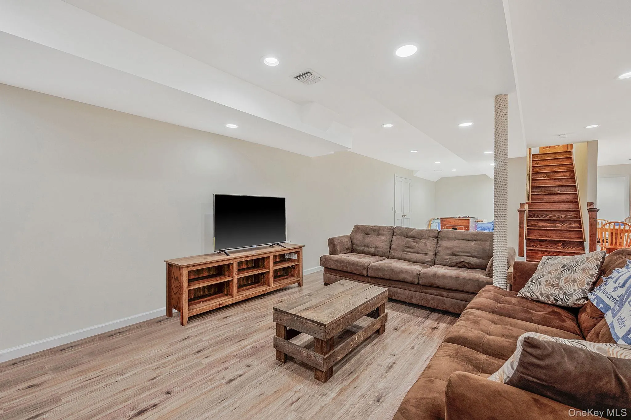 Living area with recessed lighting, light wood finished floors, and stairs Living area with recessed lighting, light wood finished floors, and stairs