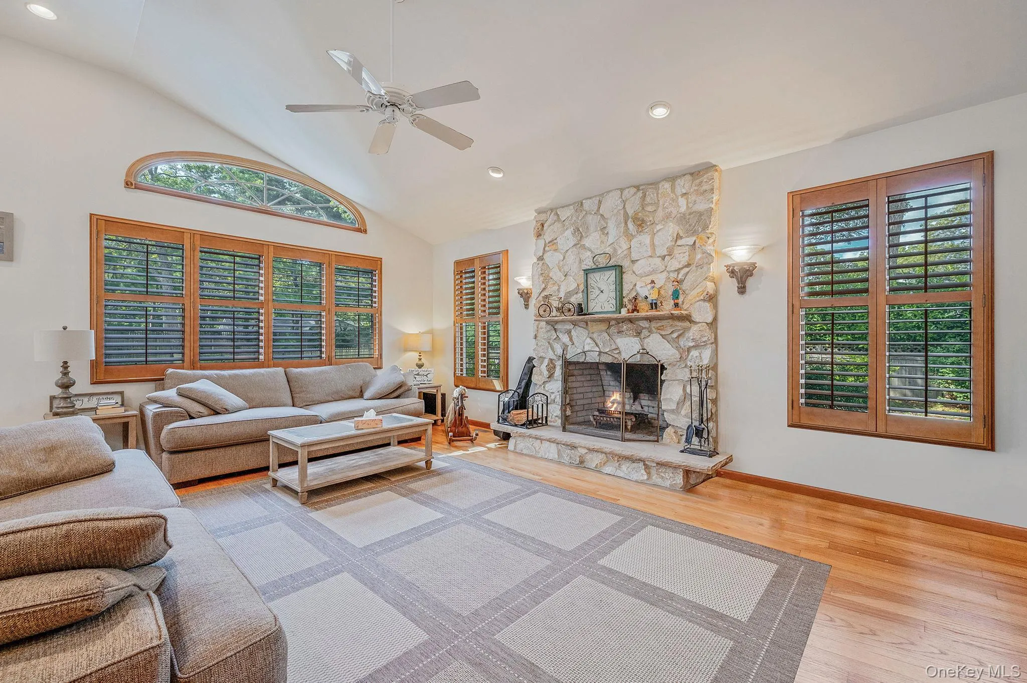 Living area featuring recessed lighting, plenty of natural light, a fireplace, ceiling fan, and high vaulted ceiling Living area featuring recessed lighting, plenty of natural light, a fireplace, ceiling fan, and high vaulted ceiling