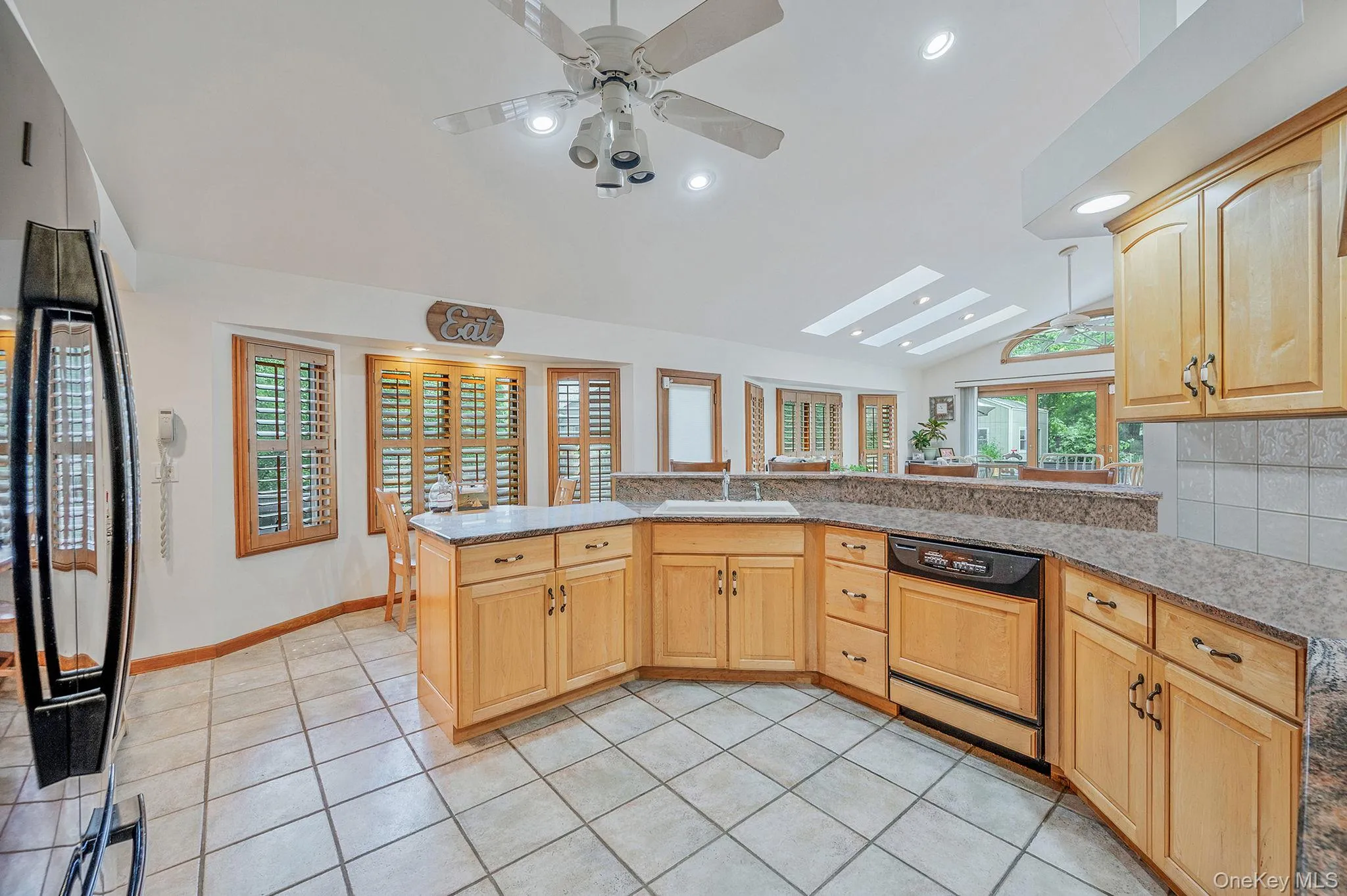 Kitchen featuring lofted ceiling, black refrigerator, dishwasher, recessed lighting, and a peninsula Kitchen featuring lofted ceiling, black refrigerator, dishwasher, recessed lighting, and a peninsula