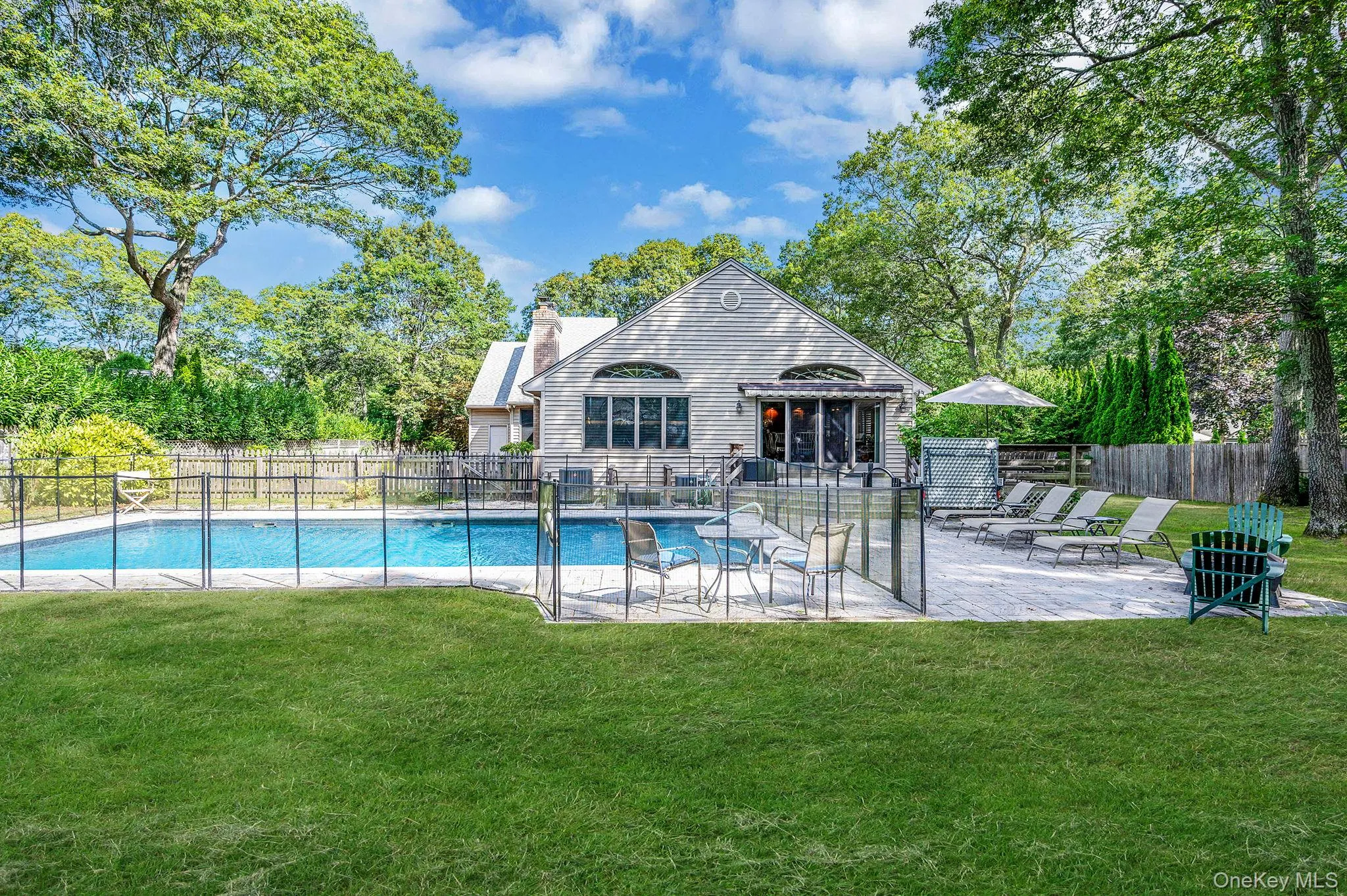 View of swimming pool featuring a patio and view of wooded area View of swimming pool featuring a patio and view of wooded area