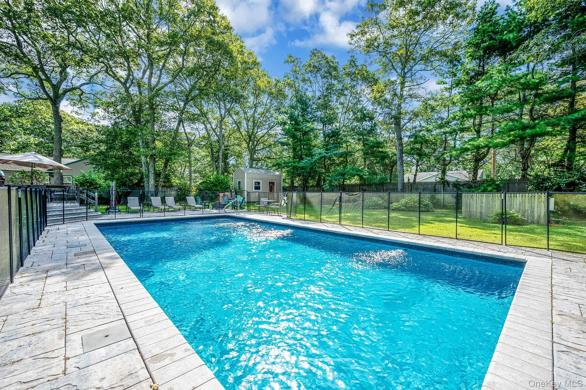 View of pool featuring a fenced backyard, a patio area, an outdoor structure, and view of wooded area View of pool featuring a fenced backyard, a patio area, an outdoor structure, and view of wooded area
