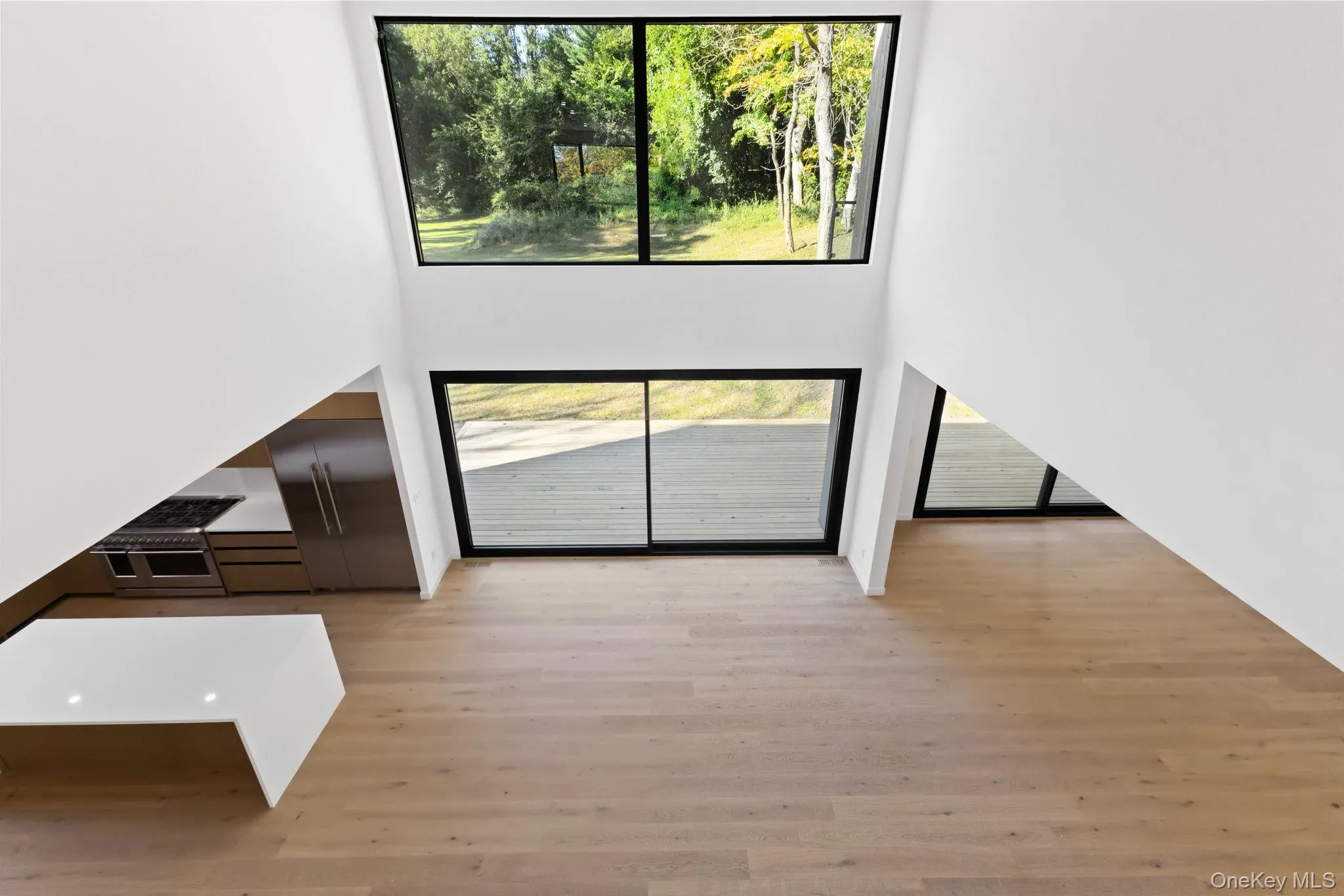 Unfurnished living room with a towering ceiling and light wood finished floors Unfurnished living room with a towering ceiling and light wood finished floors