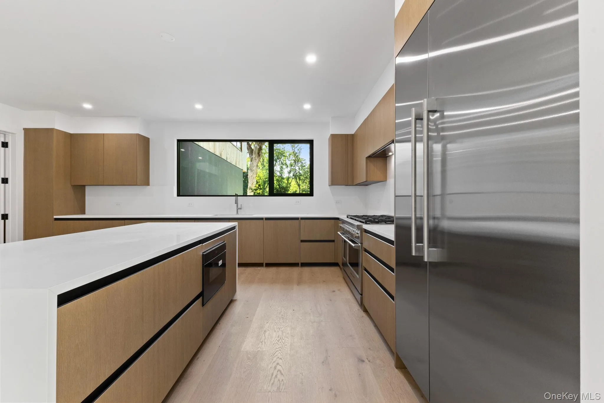 Kitchen featuring modern cabinets, high end appliances, light wood-style floors, light stone counters, and recessed lighting Kitchen featuring modern cabinets, high end appliances, light wood-style floors, light stone counters, and recessed lighting