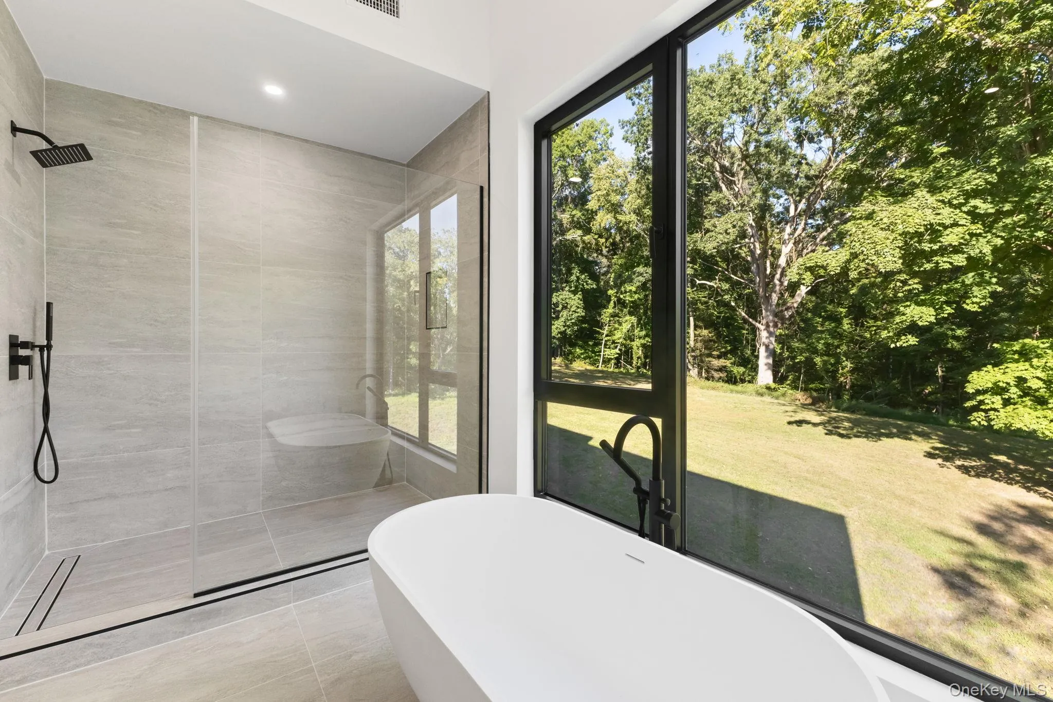 Bathroom with a stall shower, a freestanding tub, light tile patterned floors, and recessed lighting Bathroom with a stall shower, a freestanding tub, light tile patterned floors, and recessed lighting