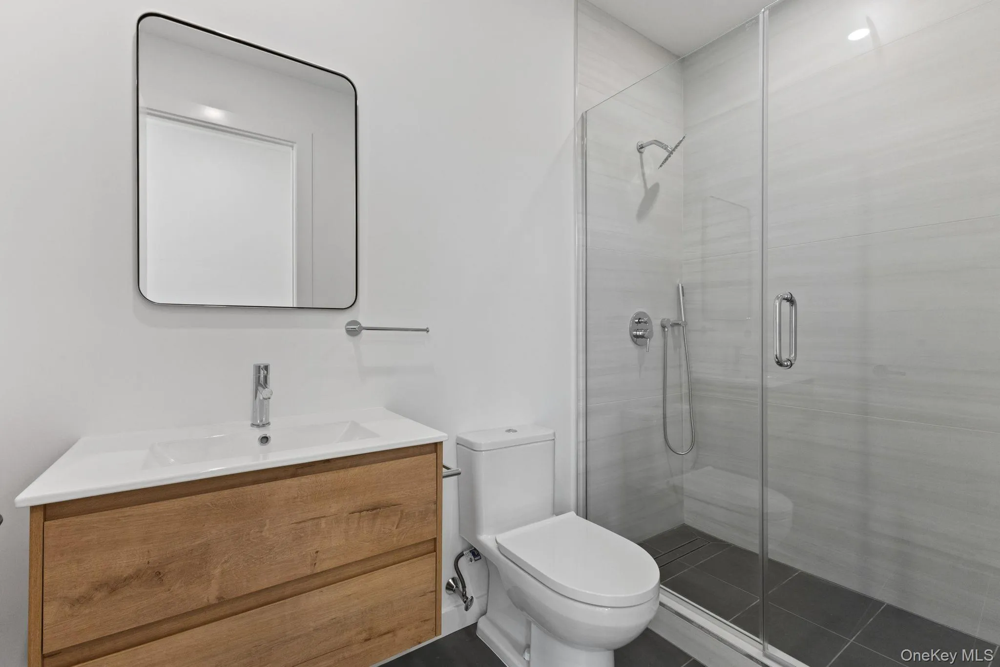 Bathroom featuring vanity, a stall shower, and dark tile patterned floors Bathroom featuring vanity, a stall shower, and dark tile patterned floors
