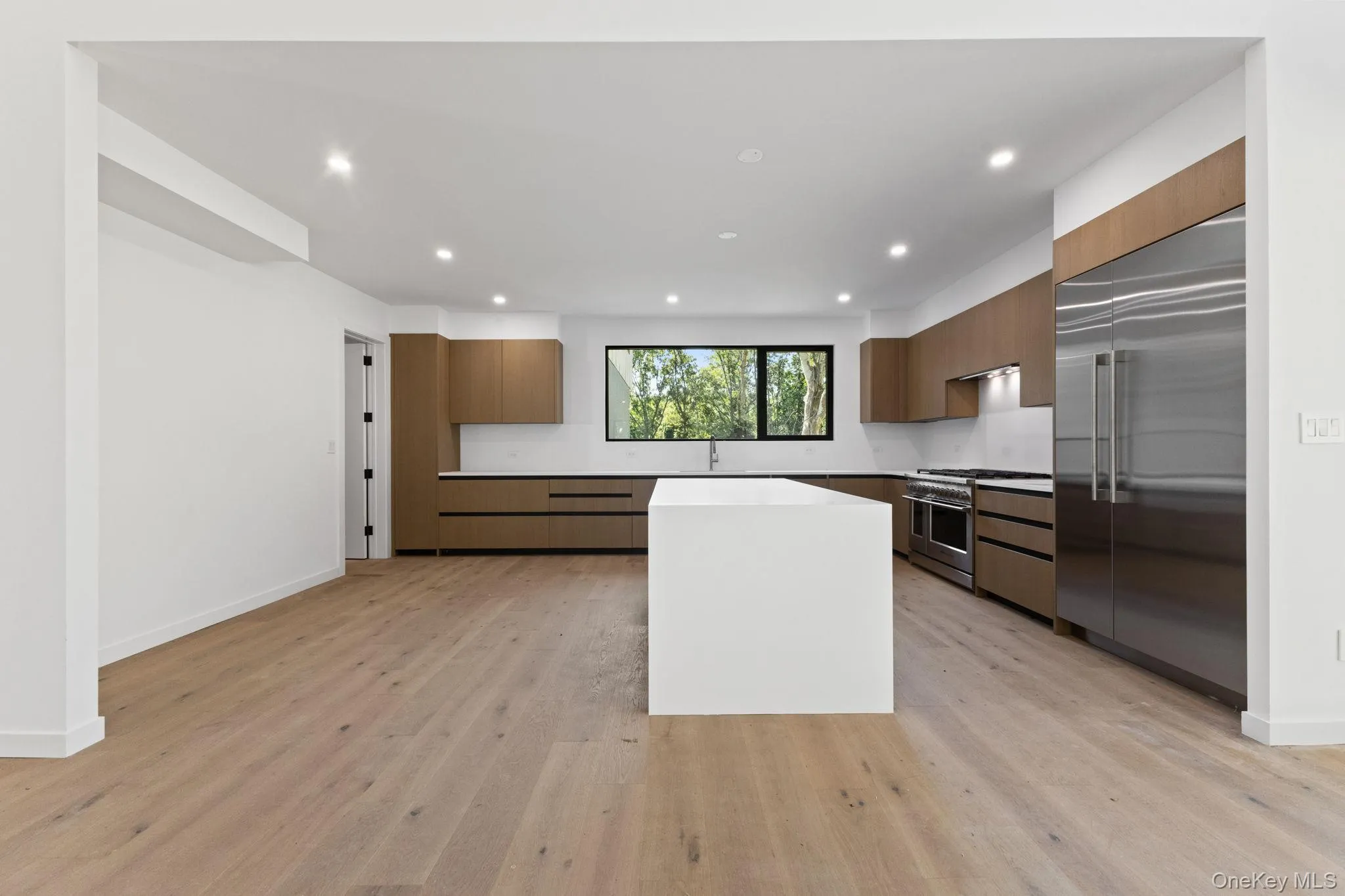 Kitchen with modern cabinets, premium appliances, recessed lighting, light wood-style floors, and brown cabinets Kitchen with modern cabinets, premium appliances, recessed lighting, light wood-style floors, and brown cabinets