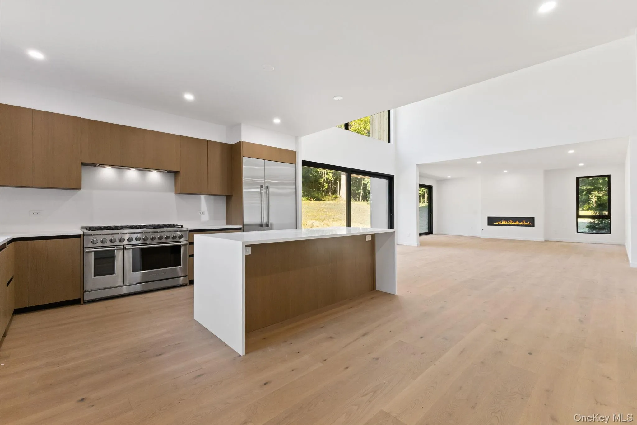 Kitchen with recessed lighting, premium appliances, modern cabinets, a kitchen island, and light wood-style floors Kitchen with recessed lighting, premium appliances, modern cabinets, a kitchen island, and light wood-style floors