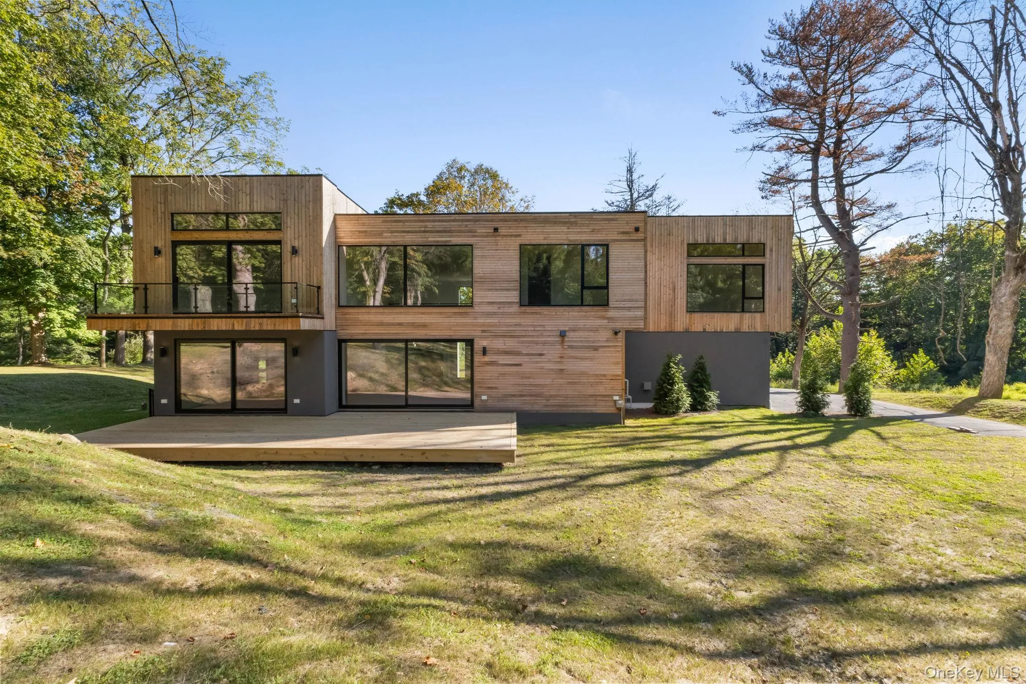 Back of house featuring a lawn, a balcony, and a wooden deck Back of house featuring a lawn, a balcony, and a wooden deck