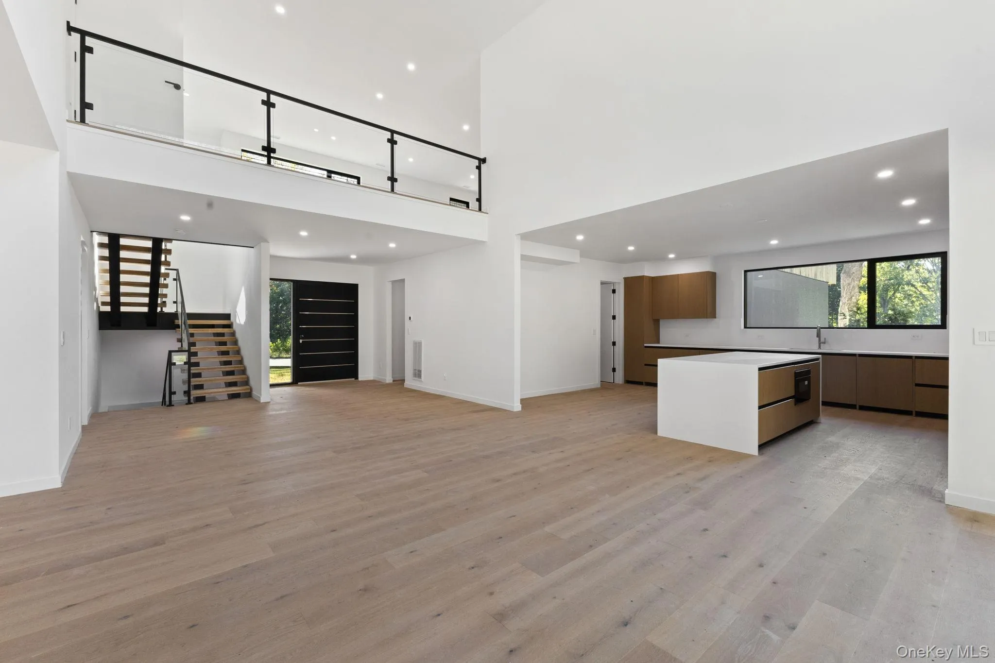 Unfurnished living room with recessed lighting, light wood-style flooring, stairway, and a towering ceiling Unfurnished living room with recessed lighting, light wood-style flooring, stairway, and a towering ceiling