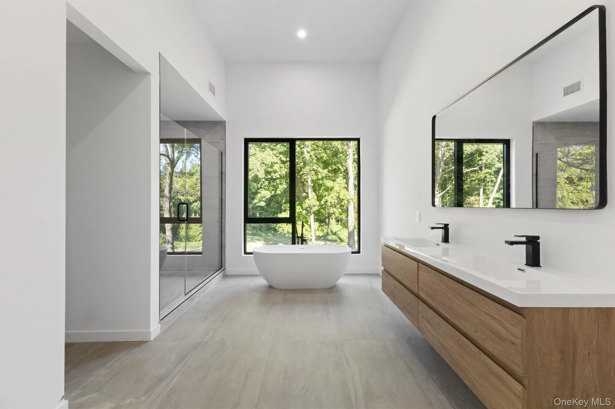 Full bathroom with a shower stall, a soaking tub, double vanity, light wood-style floors, and recessed lighting Full bathroom with a shower stall, a soaking tub, double vanity, light wood-style floors, and recessed lighting