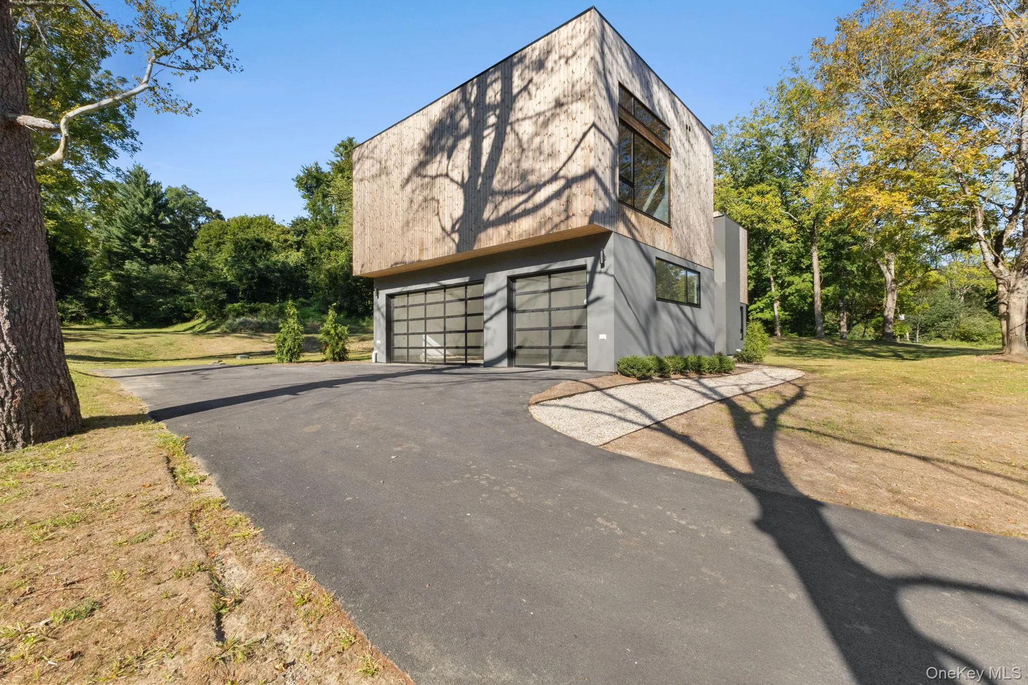View of side of property featuring a garage, a yard, stucco siding, and driveway View of side of property featuring a garage, a yard, stucco siding, and driveway