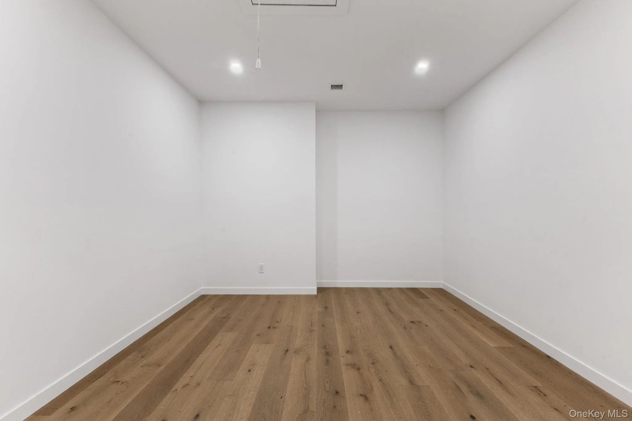 Empty room with wood finished floors and attic access Empty room with wood finished floors and attic access