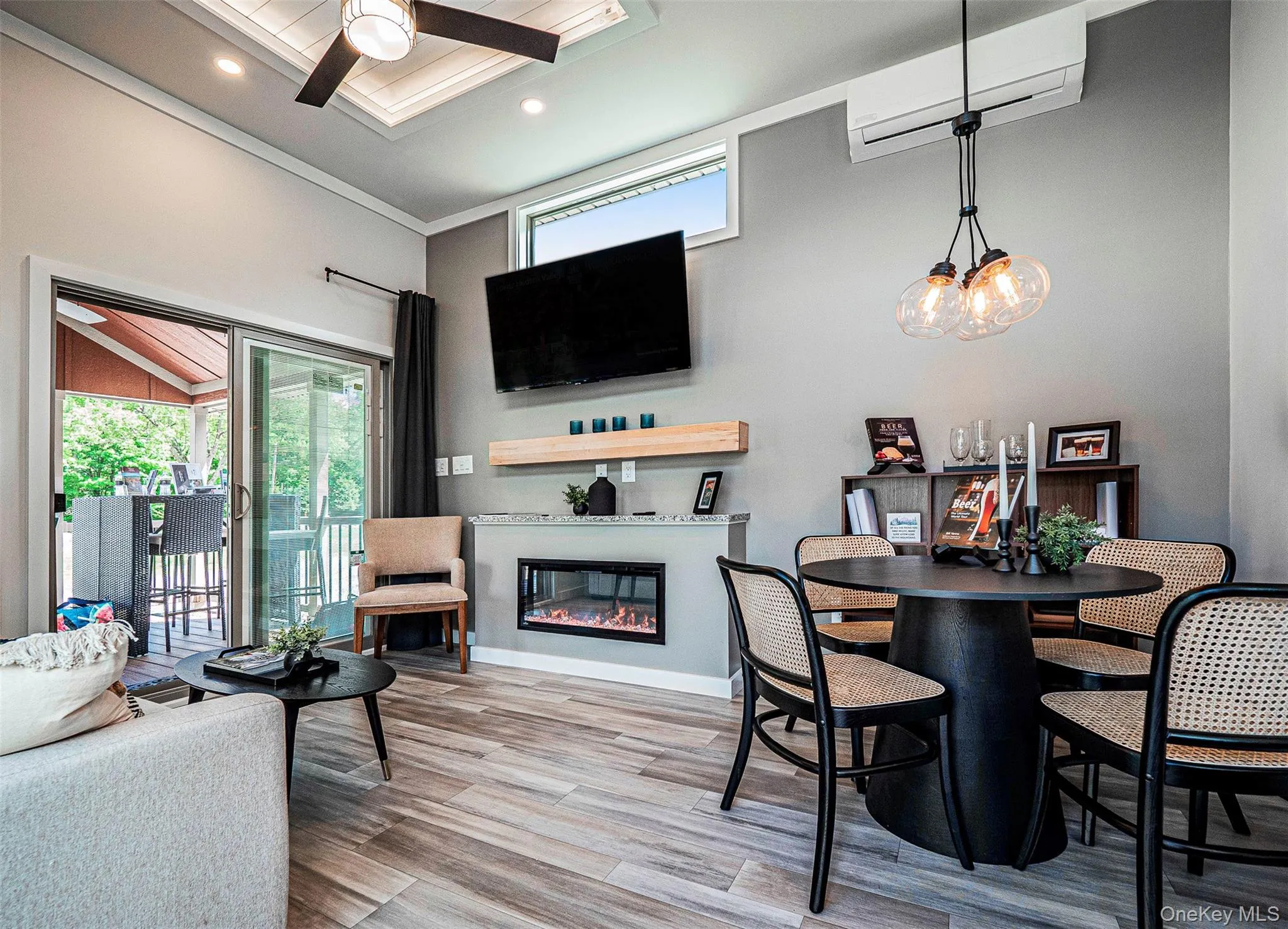 Dining space featuring a wall mounted AC, a glass covered fireplace, LVP flooring, a ceiling fan, and ornamental molding Dining space featuring a wall mounted AC, a glass covered fireplace, LVP flooring, a ceiling fan, and ornamental molding