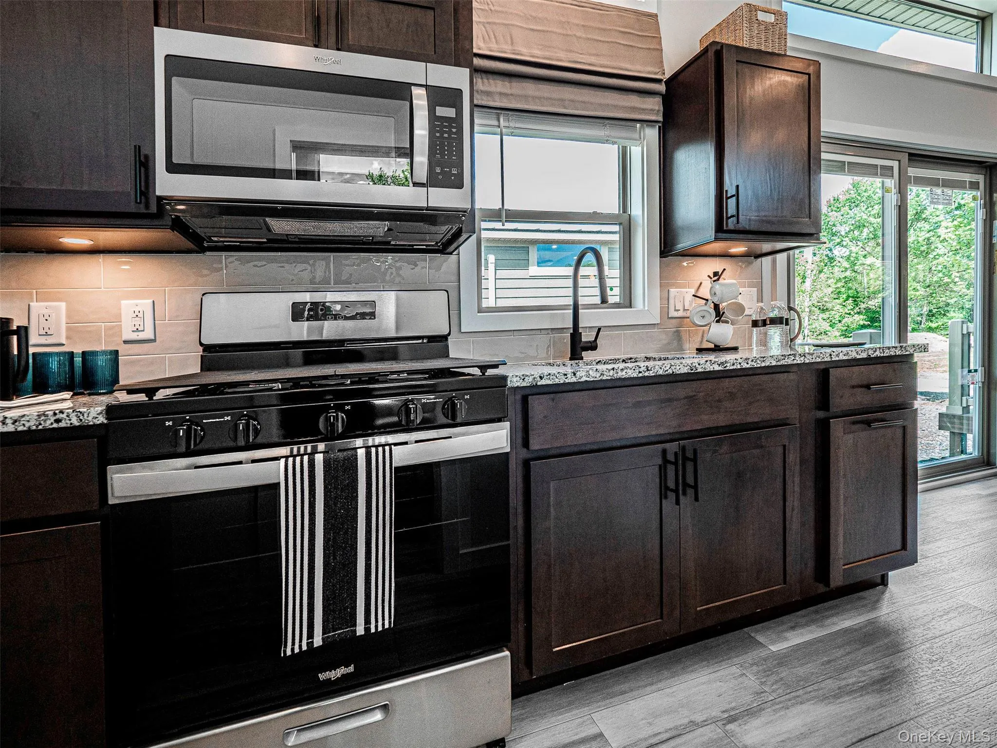 Kitchen featuring appliances with stainless steel finishes, light granite stone countertops, and decorative backsplash Kitchen featuring appliances with stainless steel finishes, light granite stone countertops, and decorative backsplash