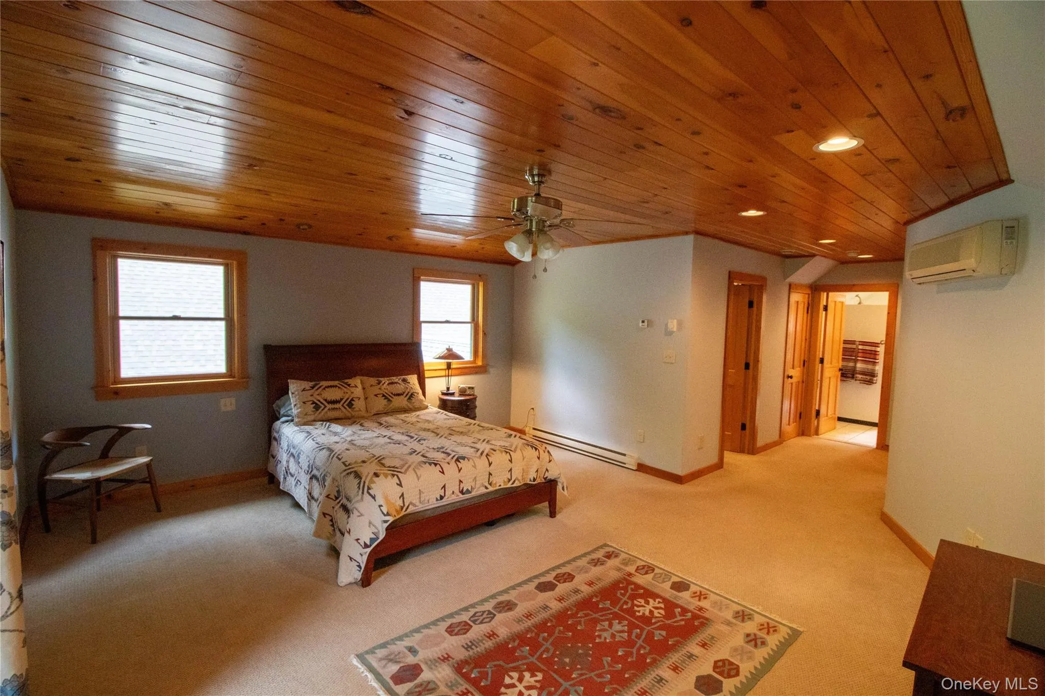 Bedroom with light colored carpet, a baseboard radiator, wooden ceiling, recessed lighting, and a wall mounted AC Bedroom with light colored carpet, a baseboard radiator, wooden ceiling, recessed lighting, and a wall mounted AC