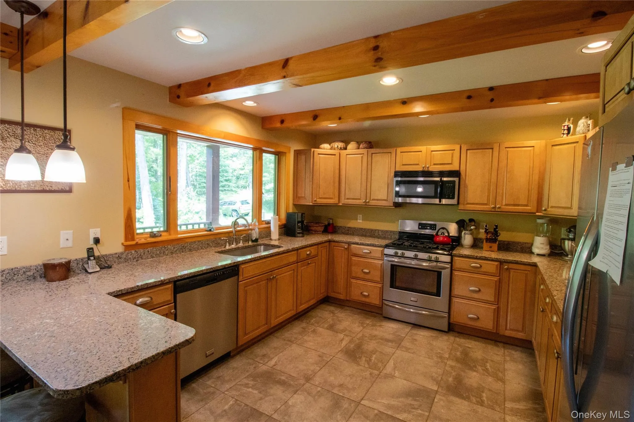 Kitchen featuring light stone countertops, appliances with stainless steel finishes, pendant lighting, beamed ceiling, and recessed lighting Kitchen featuring light stone countertops, appliances with stainless steel finishes, pendant lighting, beamed ceiling, and recessed lighting