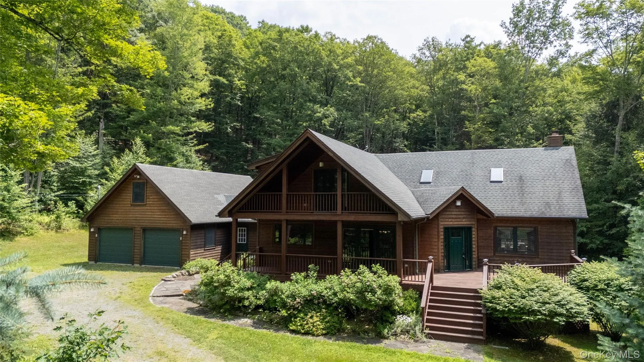 View of front facade featuring a garage, a porch, a wooded view, and a shingled roof View of front facade featuring a garage, a porch, a wooded view, and a shingled roof