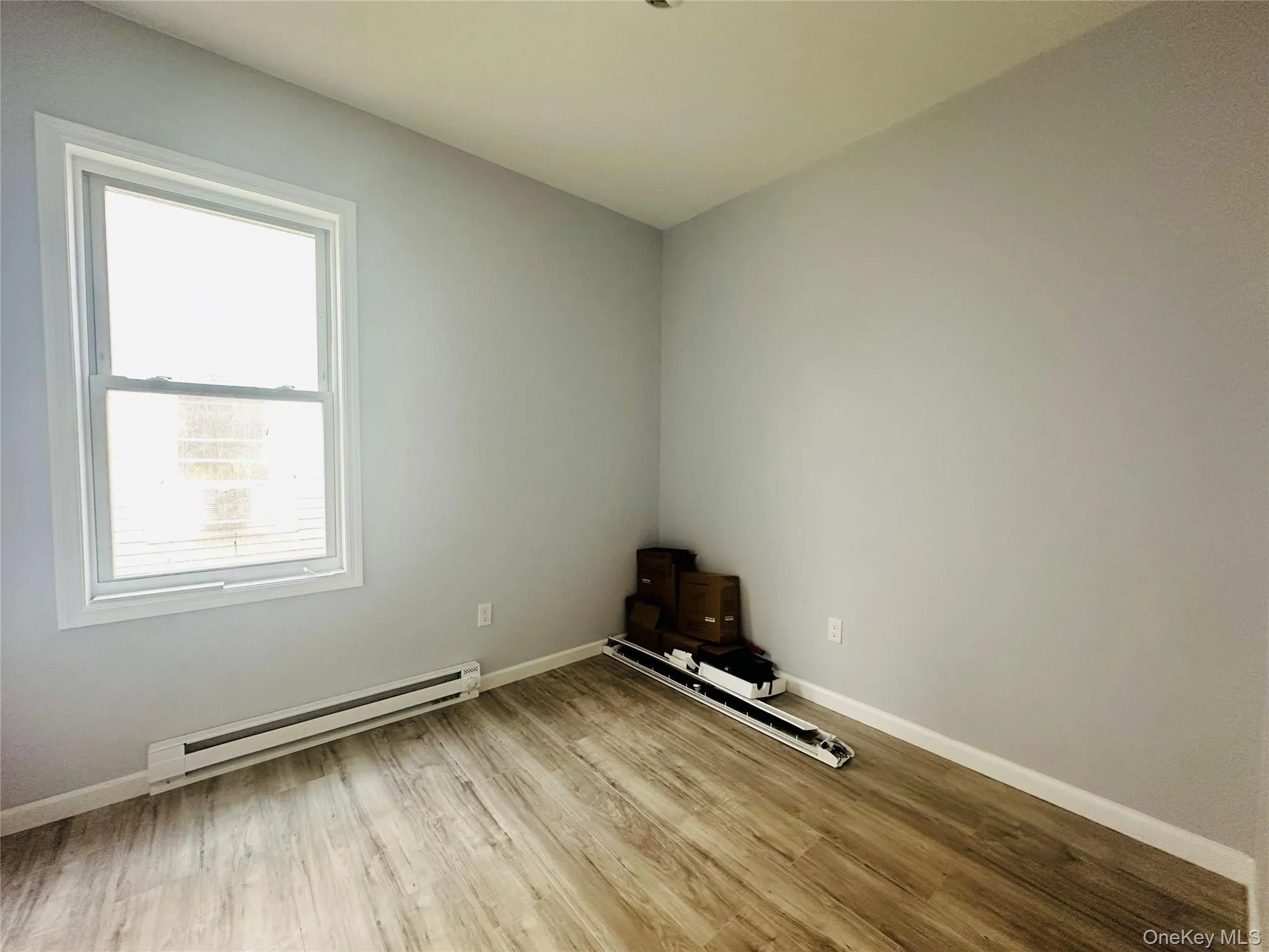Unfurnished room featuring a baseboard heating unit and light wood-style floors Unfurnished room featuring a baseboard heating unit and light wood-style floors
