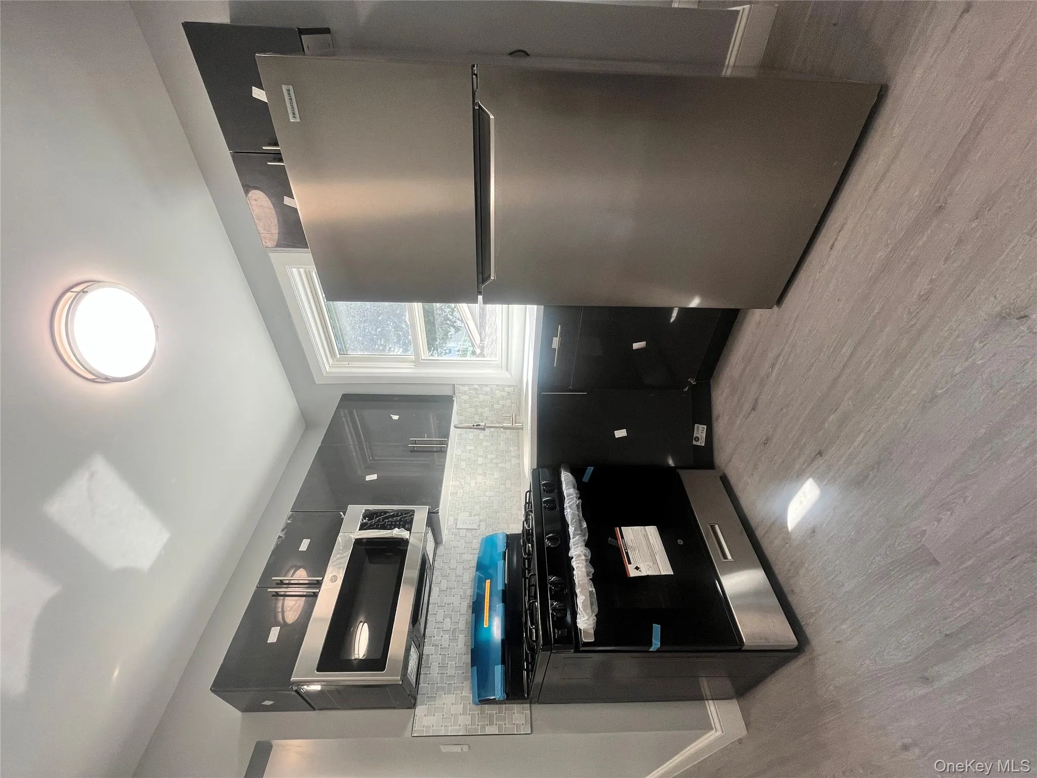 Kitchen with fridge, stainless steel range oven, tasteful backsplash, light wood-style floors, and light countertops Kitchen with fridge, stainless steel range oven, tasteful backsplash, light wood-style floors, and light countertops