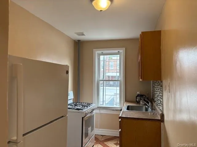Kitchen with white appliances, brown cabinets, and decorative backsplash Kitchen with white appliances, brown cabinets, and decorative backsplash