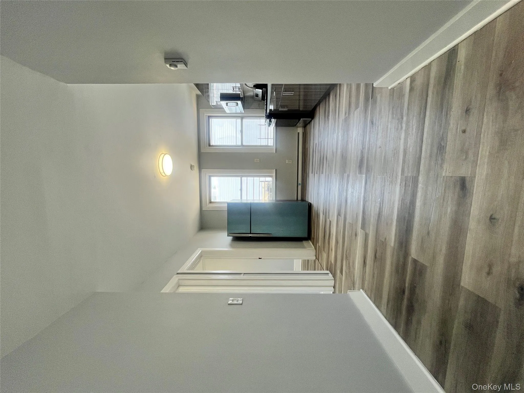 Unfurnished living room with wood finished floors and baseboard heating Unfurnished living room with wood finished floors and baseboard heating