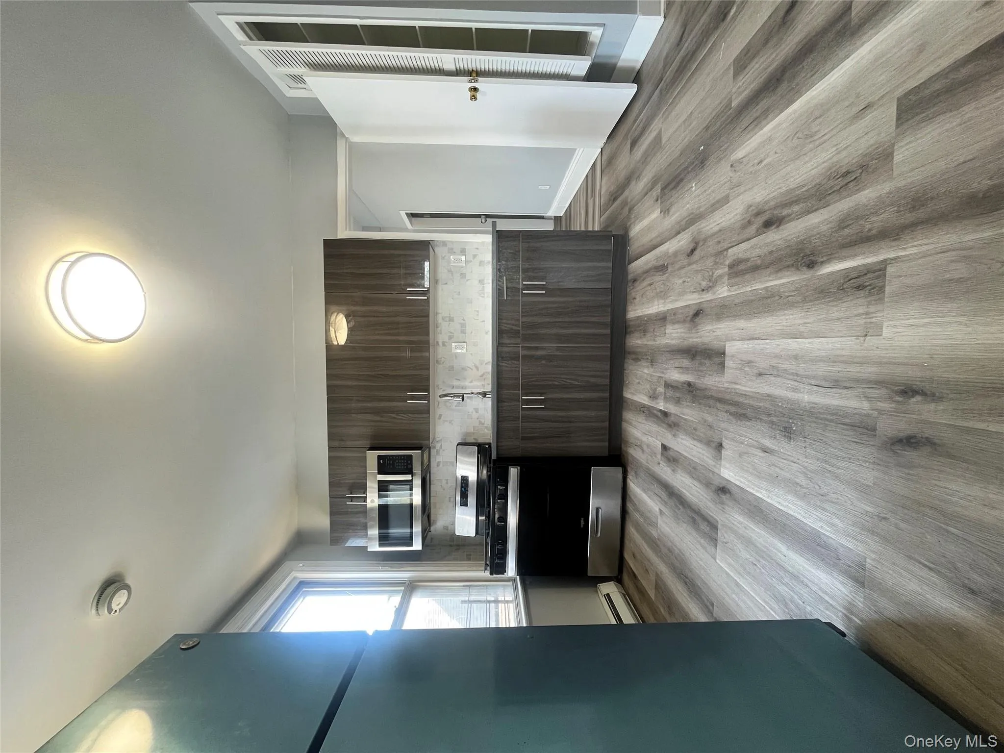 Kitchen with appliances with stainless steel finishes, dark brown cabinets, tasteful backsplash, light wood-style floors, and modern cabinets Kitchen with appliances with stainless steel finishes, dark brown cabinets, tasteful backsplash, light wood-style floors, and modern cabinets