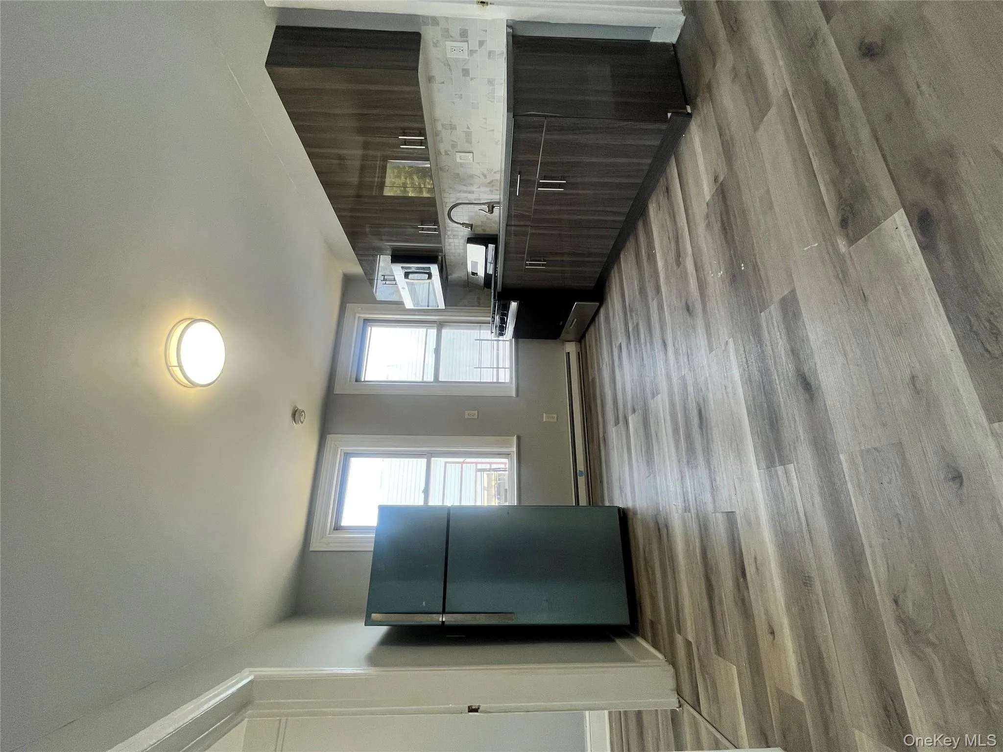 Kitchen featuring fridge, modern cabinets, stove, dark brown cabinets, and light wood-style floors Kitchen featuring fridge, modern cabinets, stove, dark brown cabinets, and light wood-style floors