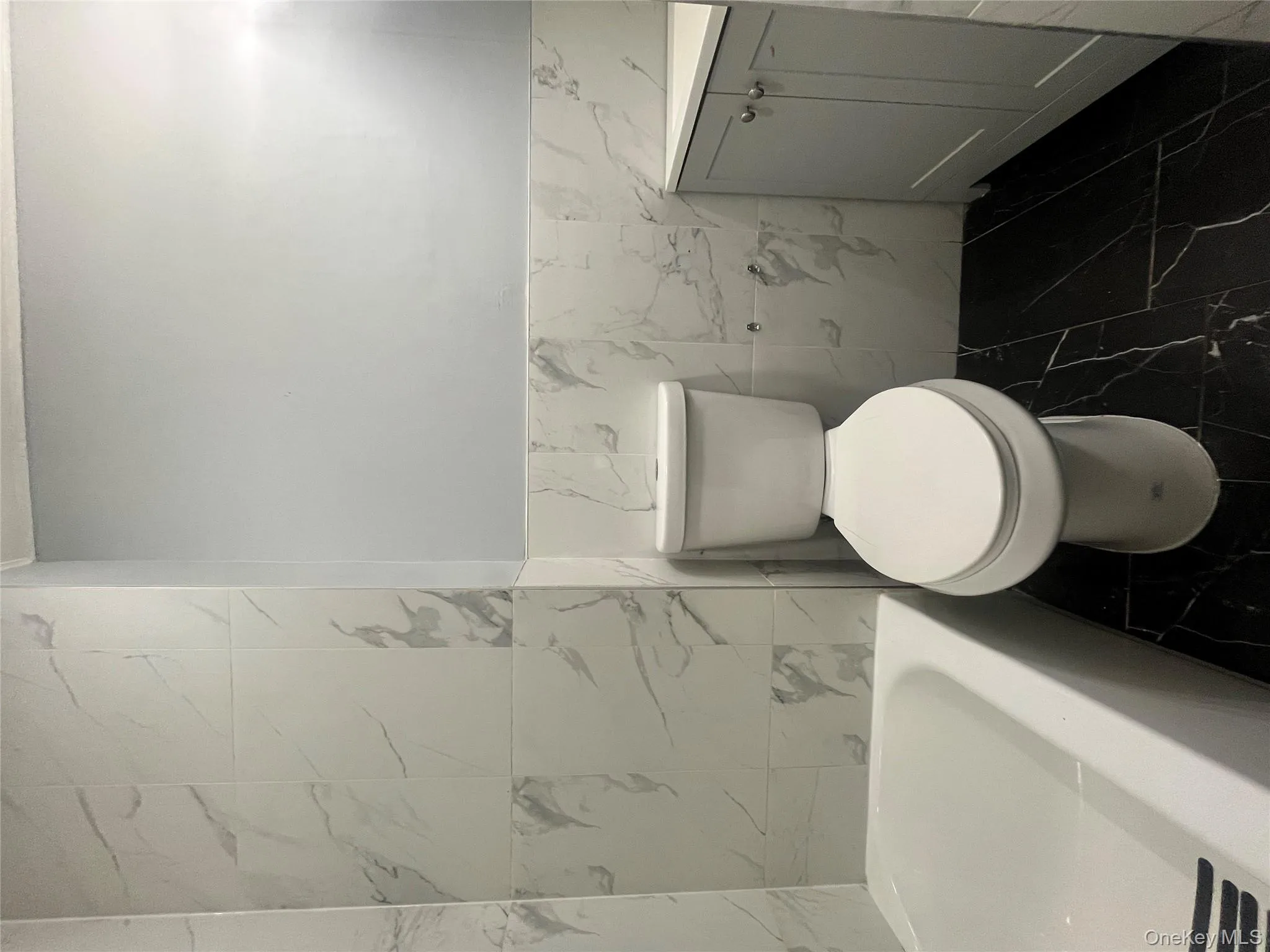 Bathroom with vanity, tile walls, a wainscoted wall, and dark marble finish floors Bathroom with vanity, tile walls, a wainscoted wall, and dark marble finish floors