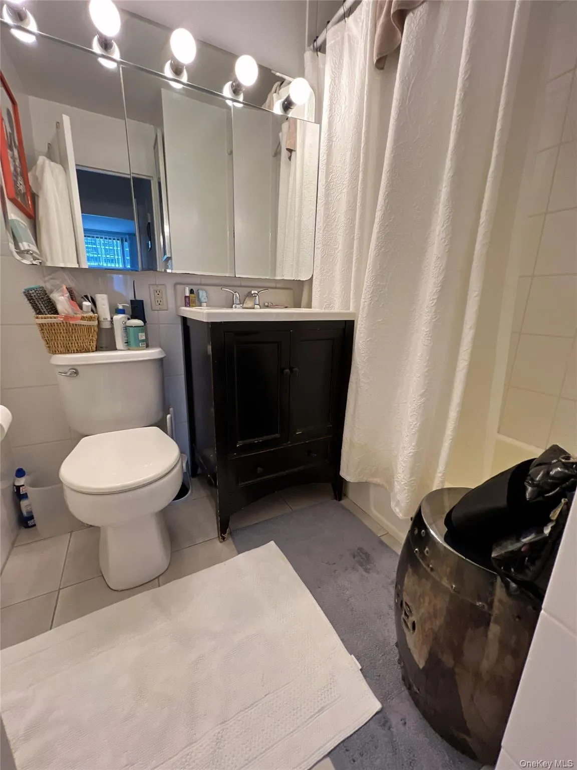 Bathroom featuring tile patterned flooring, vanity, shower / bath combo, and tile walls Bathroom featuring tile patterned flooring, vanity, shower / bath combo, and tile walls