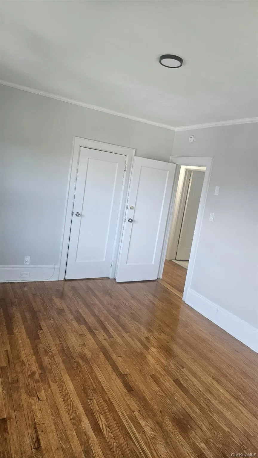 Empty room featuring crown molding and wood finished floors Empty room featuring crown molding and wood finished floors